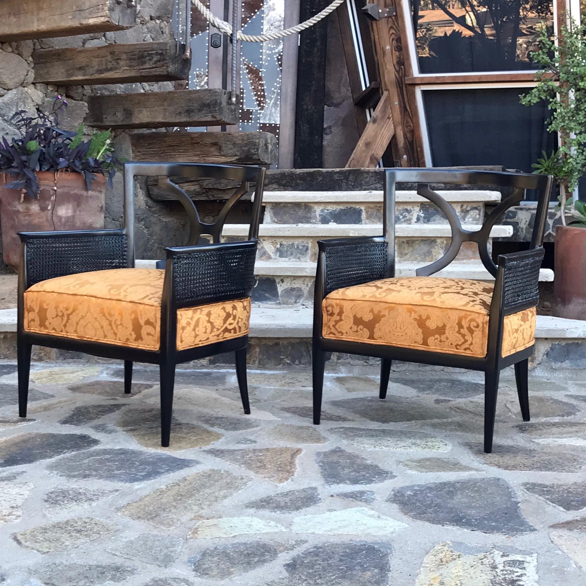 Mexican Hollywood Regency elegant pair of stately armchairs in satin black mahogany wood, sides of cane and covered in a rich gold silk brocade fabric.
No maker label available. 
Presents in the style of Roberto & Mito Block for Mexican Modernism