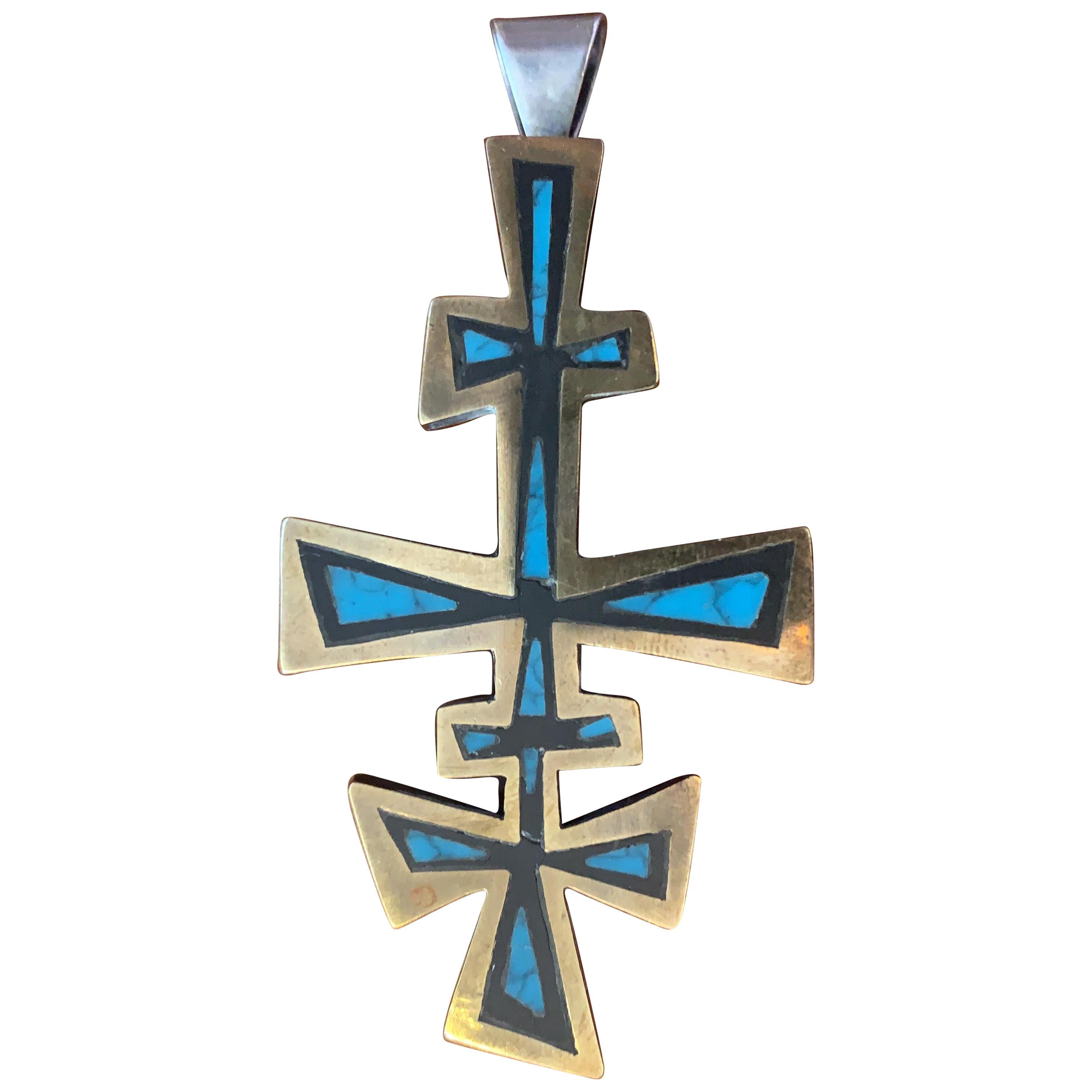 An important Mexican Mid-Century Modern sterling silver, black onyx, brass and chrysocolla pendant cross by Los Castillo. Taxco, Mexico, circa 1960. The pendant resembles a geometrical four-barred cross with brass edge, onyx body and chrysocolla