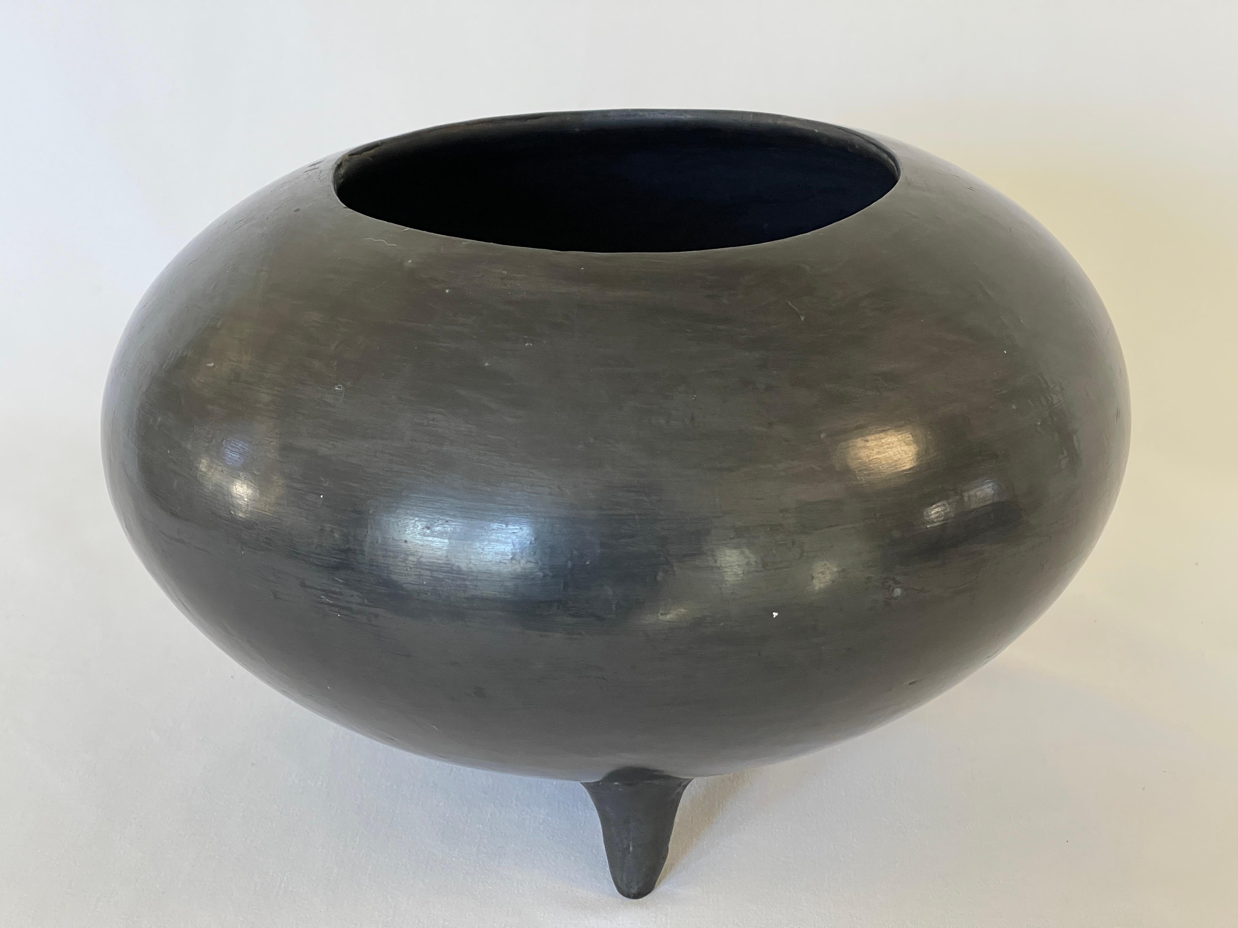 Mexican Mid century hand crafted burnished black pottery vessel raised on three graceful legs. One small hole present at bottom, as pictured.
Oaxaca, Mexico, c. 1950's.