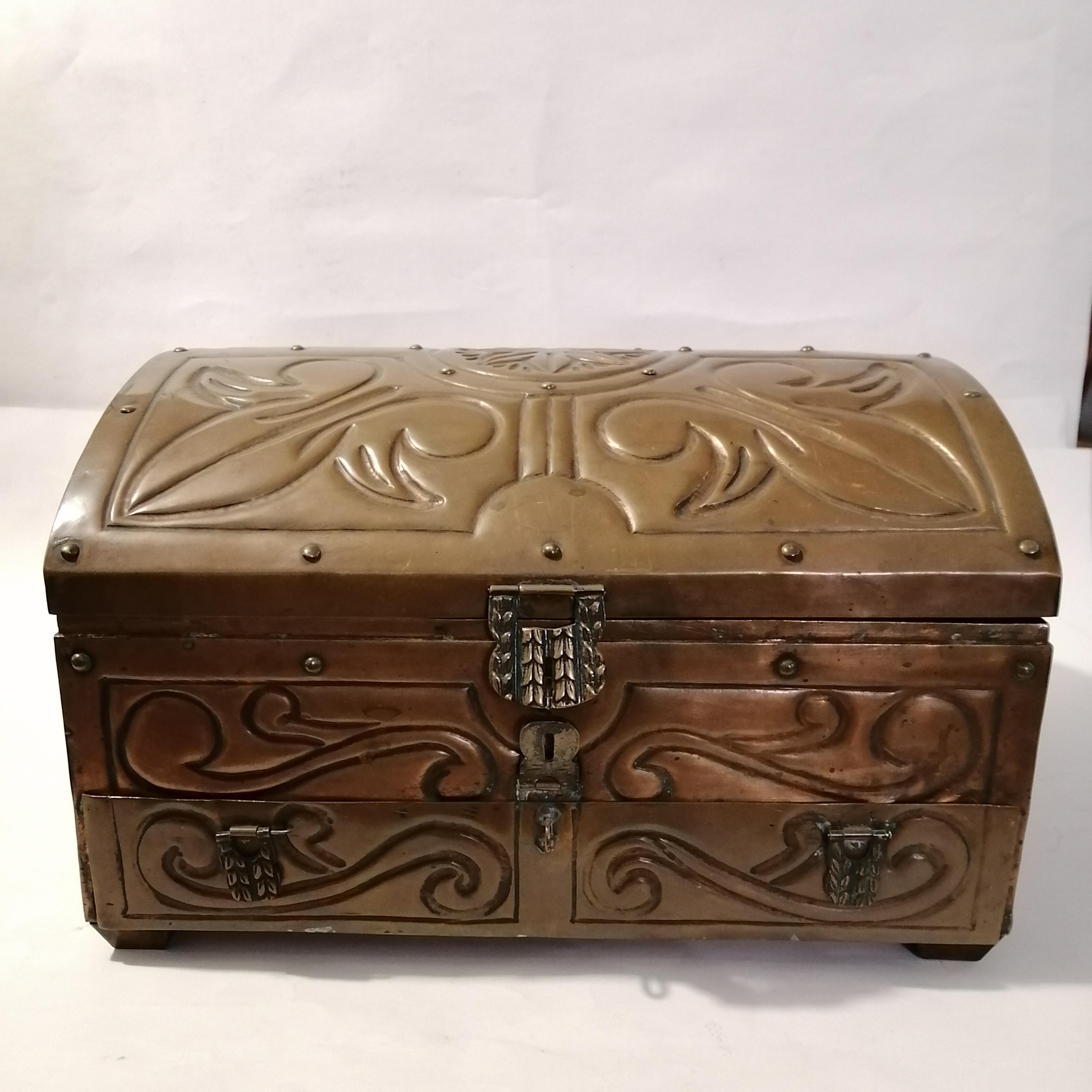 A nice Mexican Mid-Century Modern copper sheet jewel box in shape of a chest. The embossed designs show acanthus leaves and a rosette.

The jewel box's interior and removable tray show its old original green velvet dressings, which are still in a
