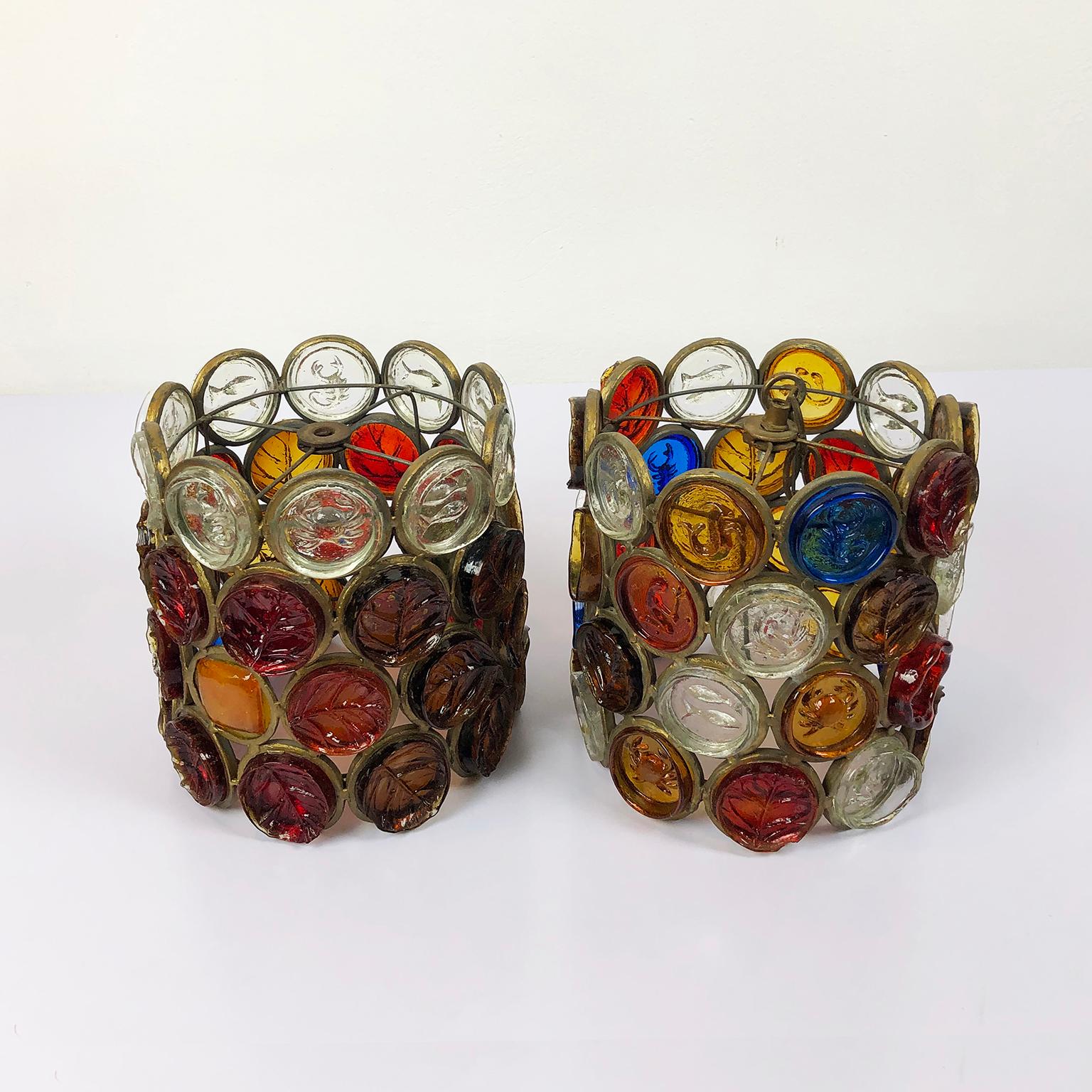 These original rare pair of pendant lights are one of the most stunning samples of Brutalist art, circa 1970. Made of iron painted in gold and multicolored blown glass, the glass pieces have zodiac and leaf designs that are distinctive designs of