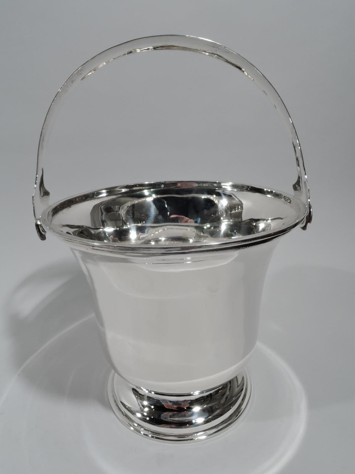 Mexican Modern sterling silver ice bucket. Bell-form bowl on raised foot. C-scroll swing handle with shaped terminals. A handy and portable bar accessory. Marked. 

Dimensions: H (with handle) 10 x W 7 x D 6 3/8 in. Weight: 17.5 troy ounces.