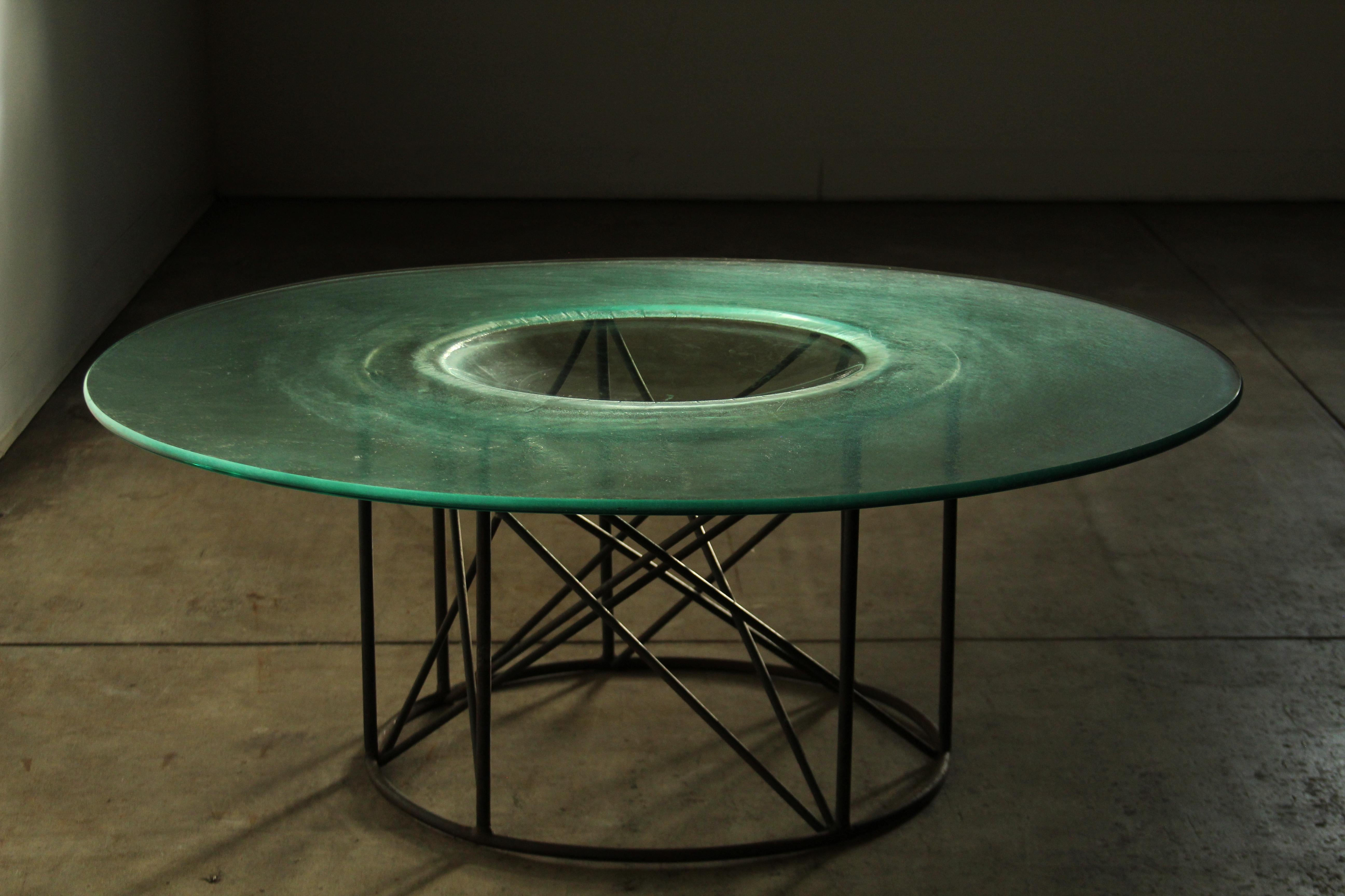 A sublime and unusual modernist coffee table which we believe was made in Mexico in the 1970s. Beautiful welded, steel base with crisscrossing elements. The top consists of a large handblown piece of green tinted glass with rounded edges and a