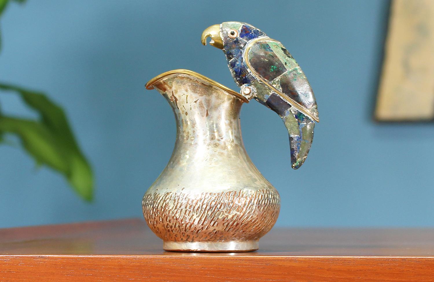 Small silver pitcher designed and manufactured by Los Castillo in Mexico circa 1950’s. Crafted in silver, the pitcher shows a beautiful texture and warm patina throughout. The decorative parrot is set with abalone shells giving it a playful sheen.