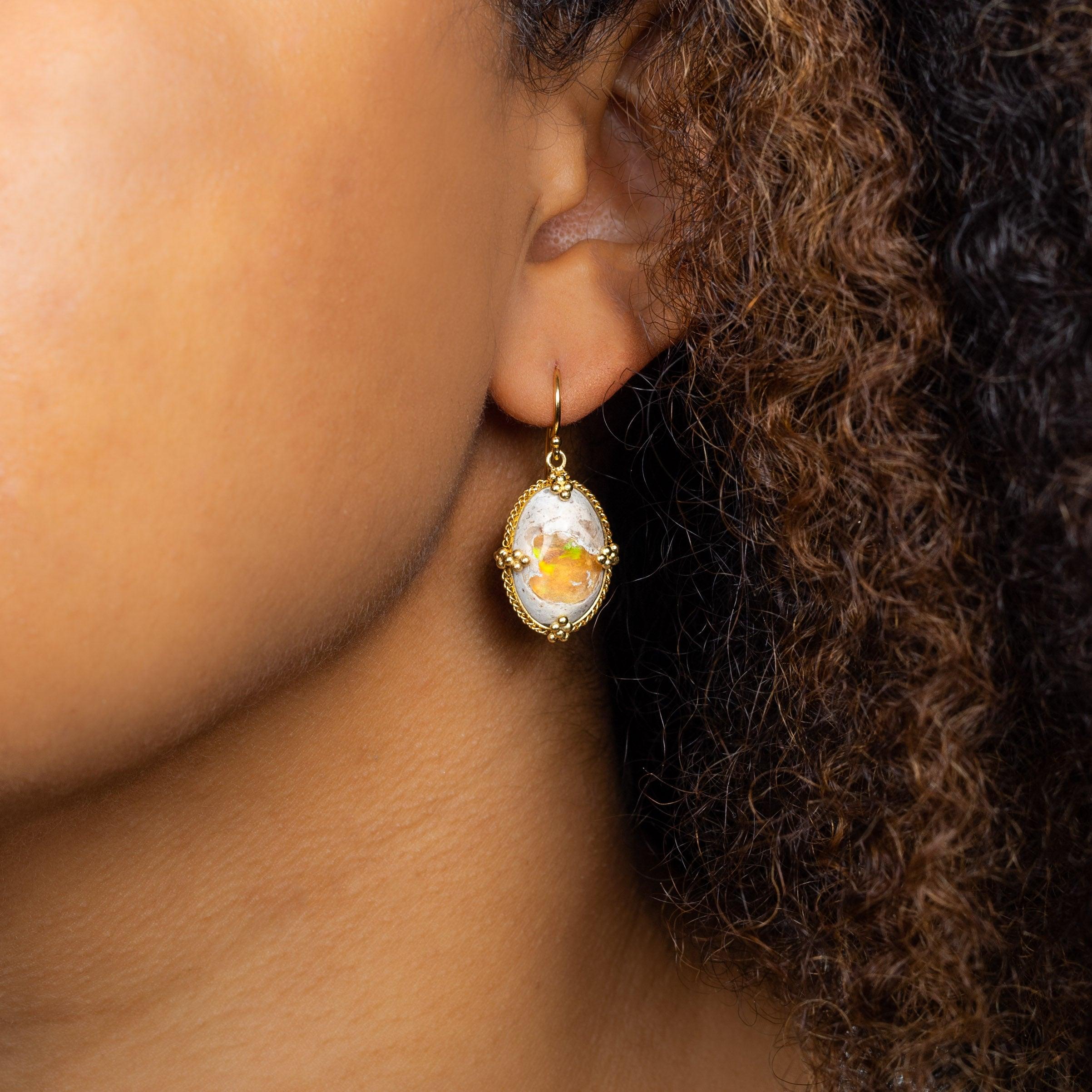 With a milky exterior giving way to a vibrant center that shimmers with the banked fire of a nearly infinite array of colors, the two Mexican Opals in these earrings feel like they could be the long-lost treasure from a dragon’s hoard. Set in gold