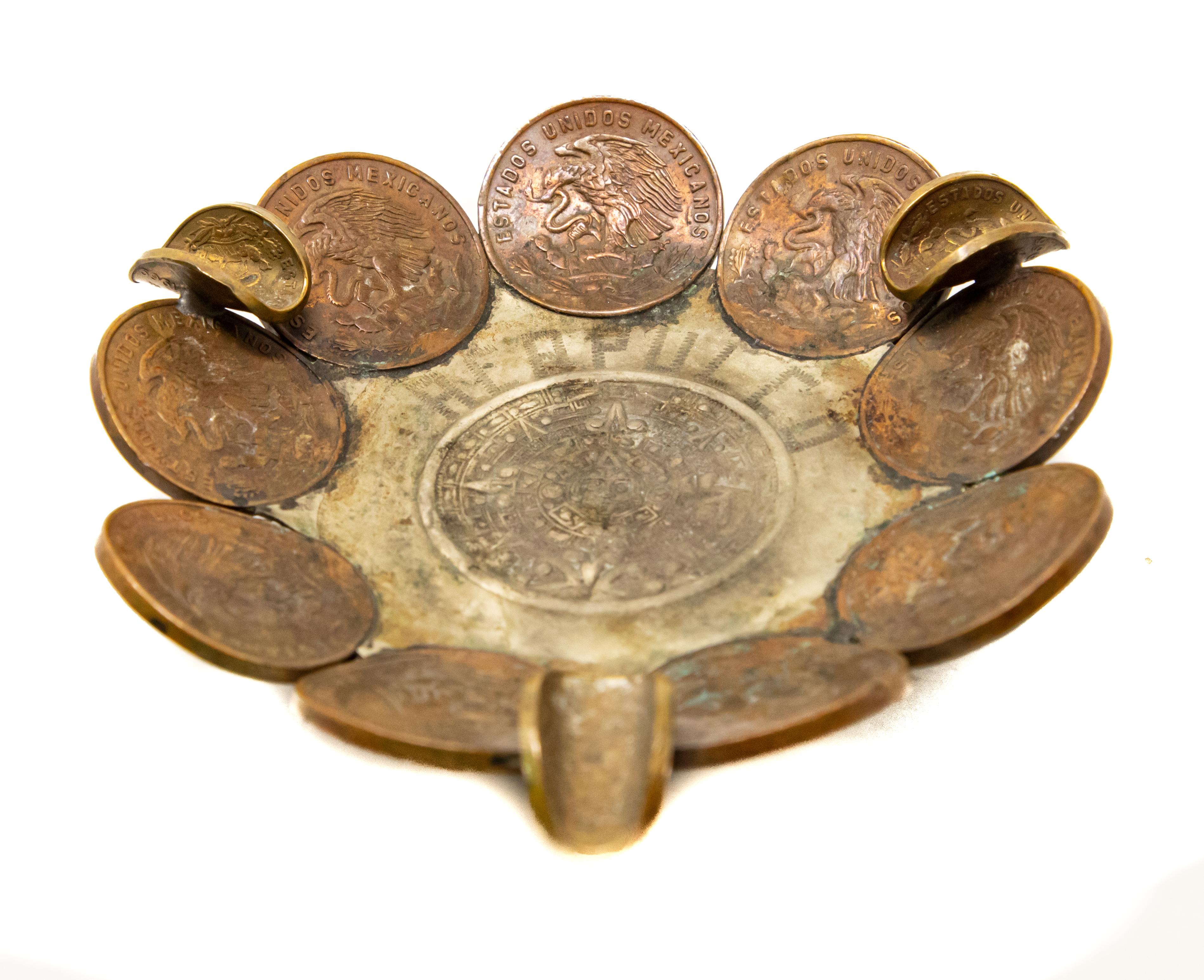 Offering this ashtray made with Mexican Pesos'. Start with three five cent pesos as the feet. The main body is made up of nine, twenty cent pesos. And has three more five cent pesos as the holder. The center is stamped with a Mayan relief and