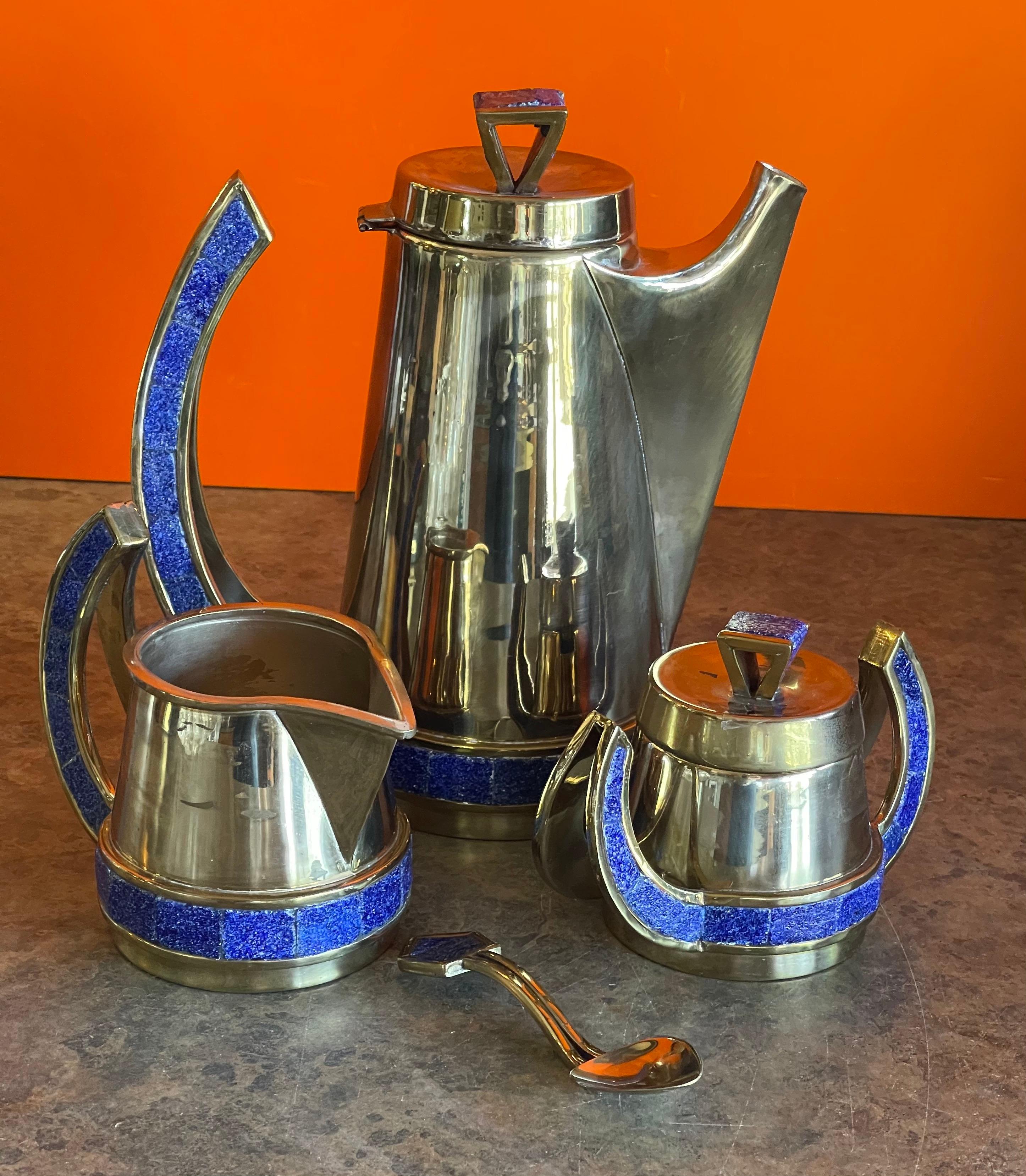Stylish Mexican plated metal & turquoise four piece coffee service set circa 1970's. The set has a coffee pot, creamer, lidded sugar bowl and a spoon which have bright blue turquoise inlaid handles and accents. The coffee pot is 7