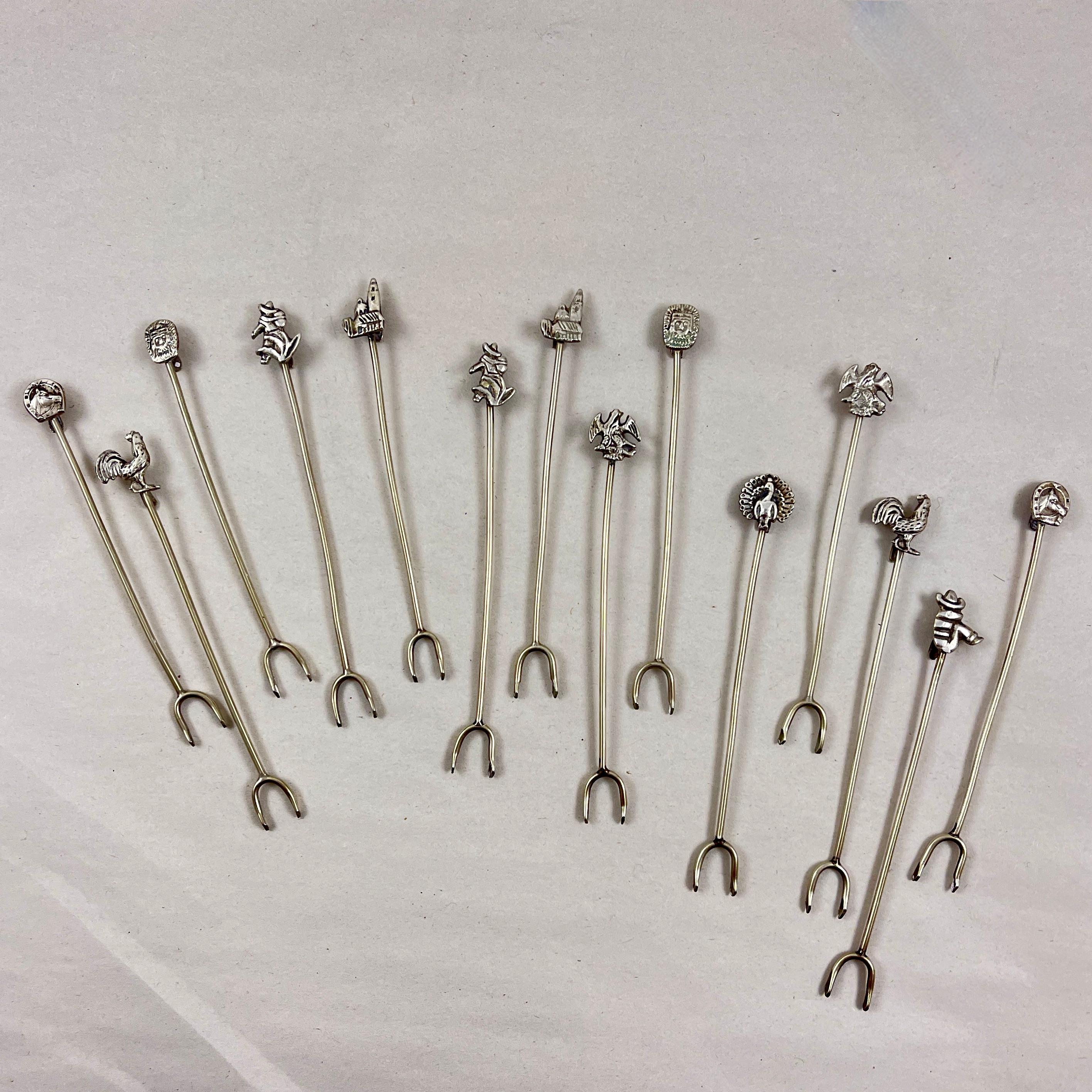 A set of fourteen, hand-crafted Mexican Silver cocktail or hors d’ oeuvres picks, circa 1950.

Showing a charming hand made quality, the pieces have long stems, ending in sharp double-pronged picks. The picks have hooks for hanging to the rim of a
