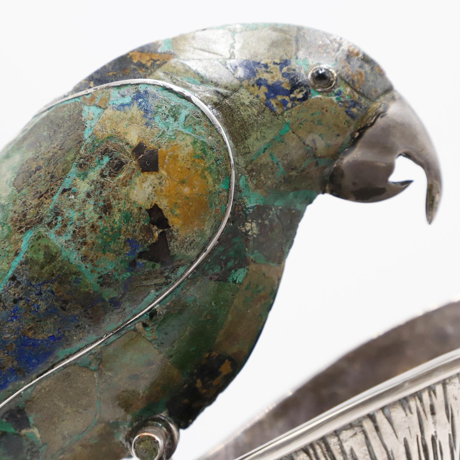 Alrededor de 1960. Te ofrecemos esta jarra mexicana de metal y malaquita que luce una asombrosa asa con motivo de loro, de Los Castillo Taxco México. Se trata de un exquisito y monumental cántaro estampado con Los Castillos, esta pieza tiene una