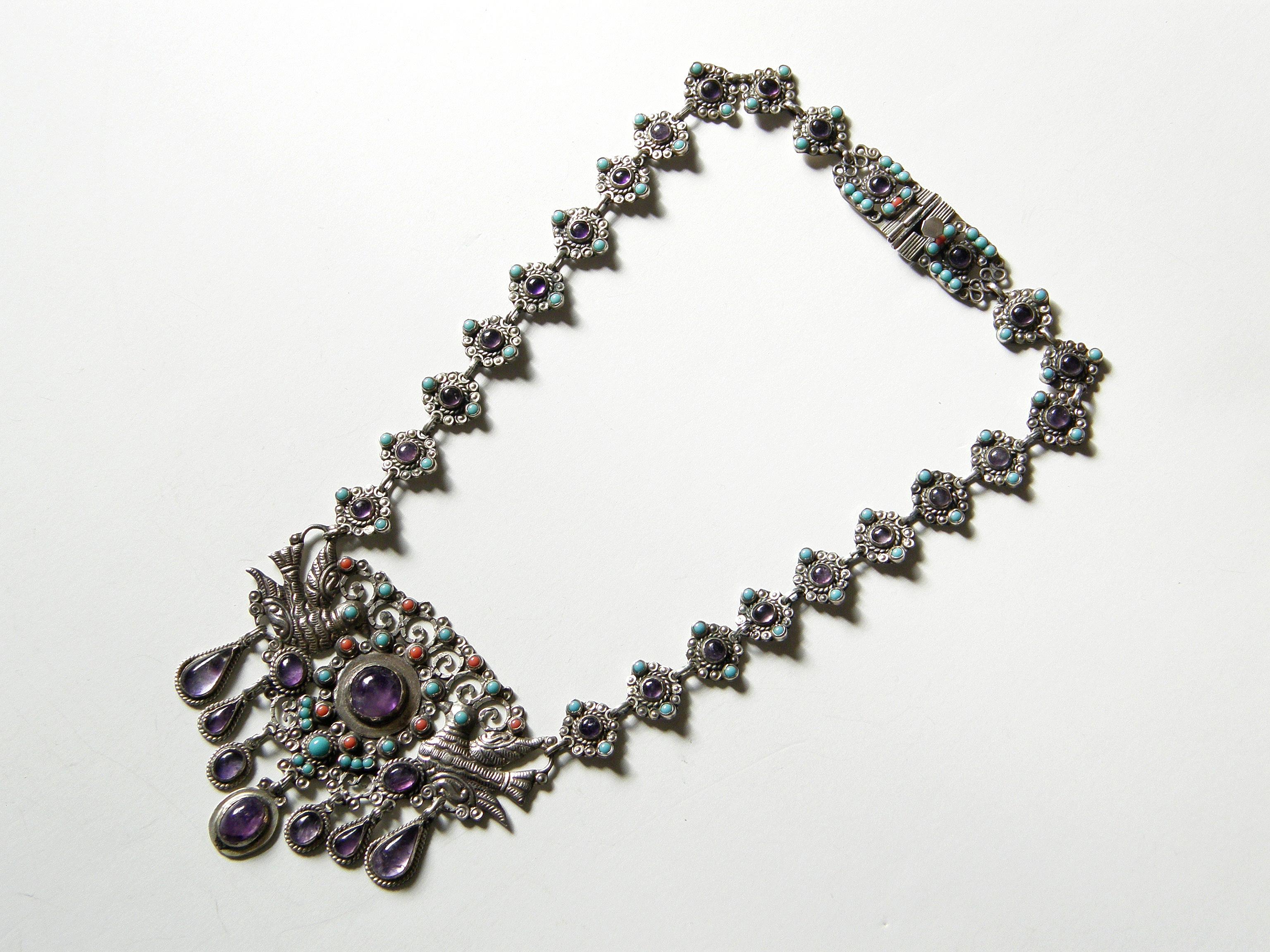 This lovely necklace and bracelet set were made in Mexico in the style of Matilda Poulat. The charming, folkloric designs are set with amethysts, turquoise and coral. The pendant features a pair of facing birds and the pleasant animation of the