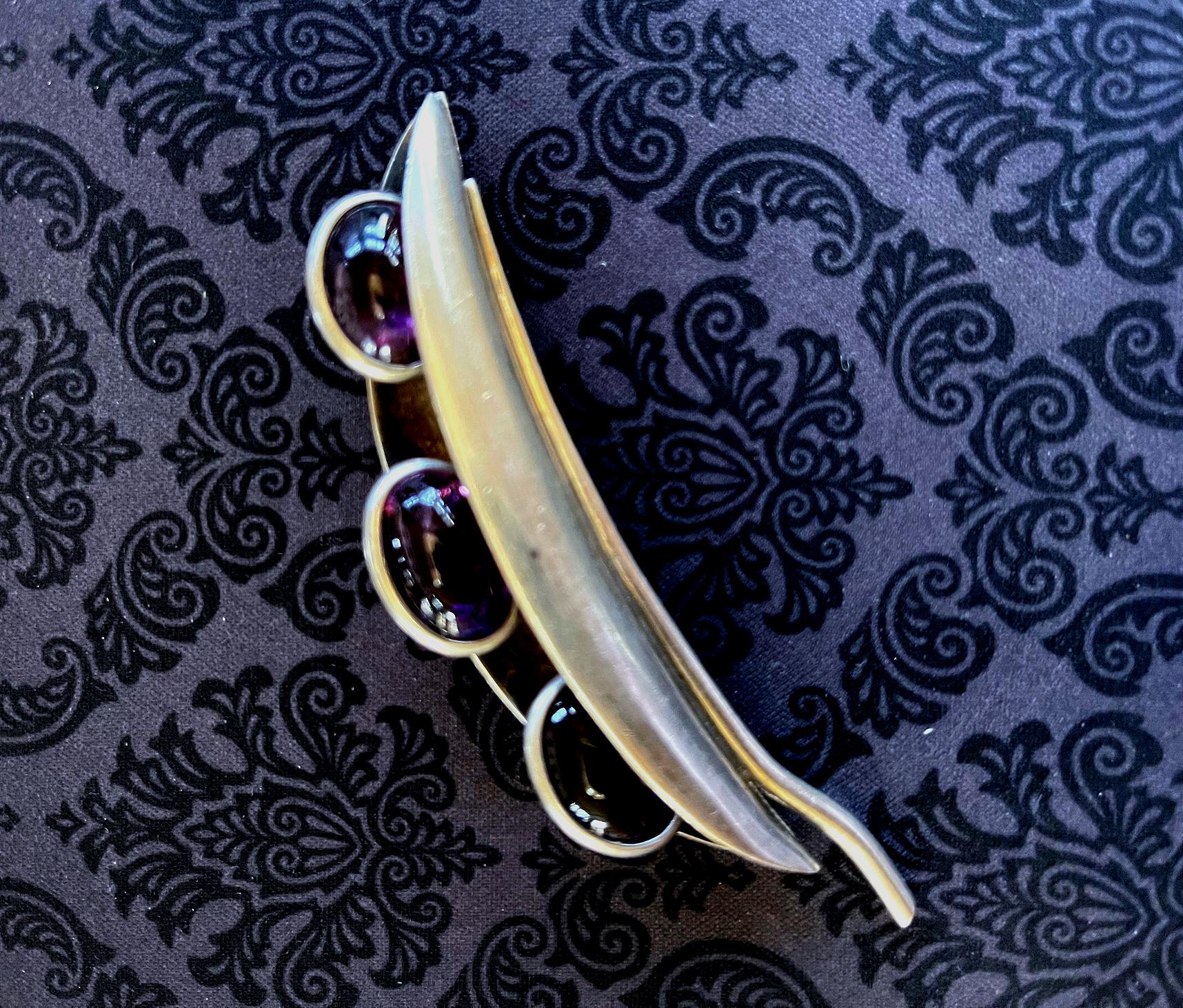 A Mid-Century Modern sterling silver brooch with three amethyst gem stones by Mexican Taxco silversmith Antonio Pineda (1919-2009). The lovely piece was created in the form of a peapod with amethyst as the peas. It is marked verso model number