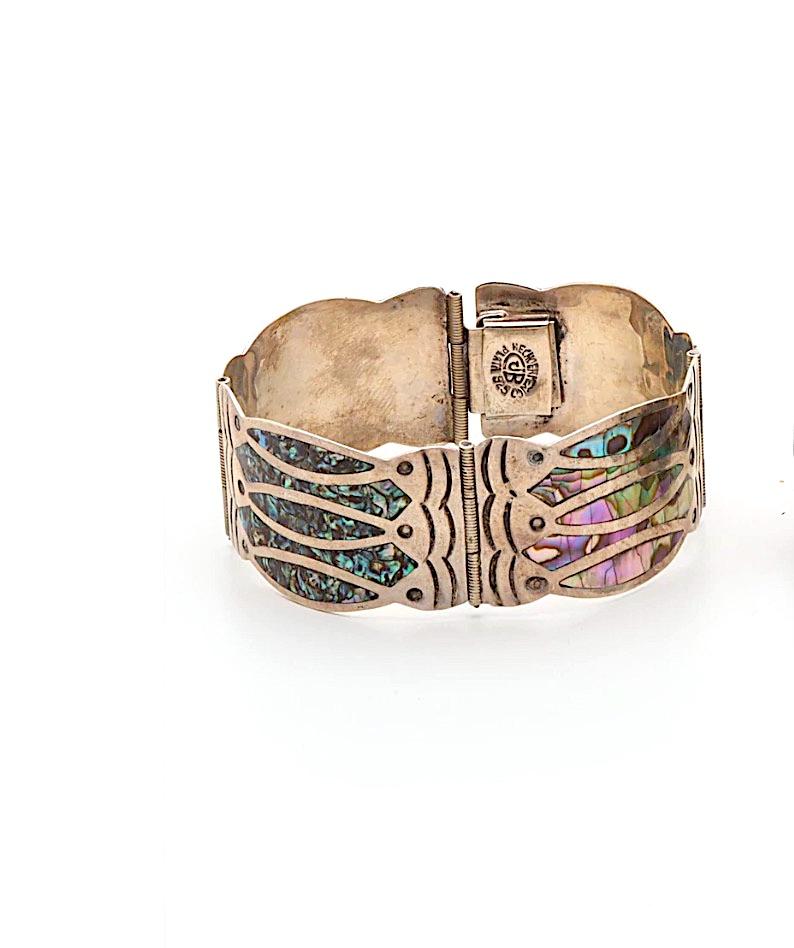 Featured is a Diaz Santoyo bracelet inlaid with abalone in a Fish Design with four contoured links with concentric designs. 

Metal Type: Sterling Silver
Length: 6.25