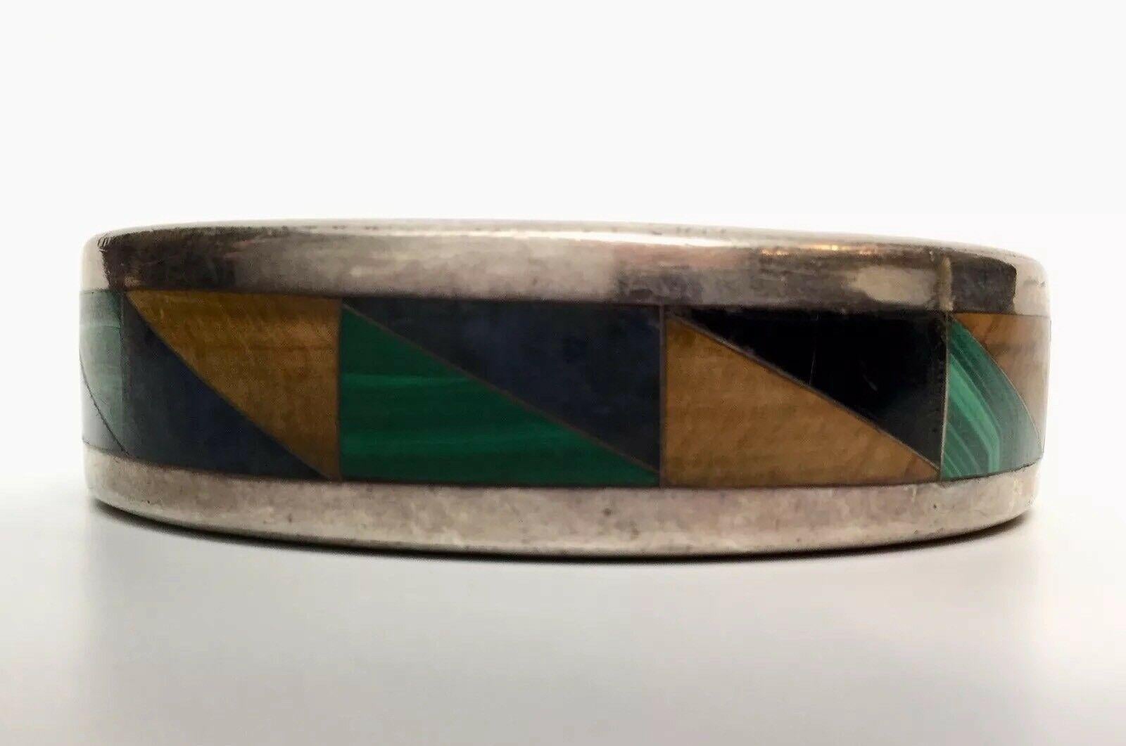 Mexican Sterling Silver Inlay Bangle Multi Stone 

Marked: TM-207 Mexico 925

Signed: CRYS

Measurements:

2 3/4” wide

Approximately measures 6 3/4” end to end

1/4” thick, 11/16” high

Weight: 56.4 dwt, 87.7 g

Bangle in very good condition with