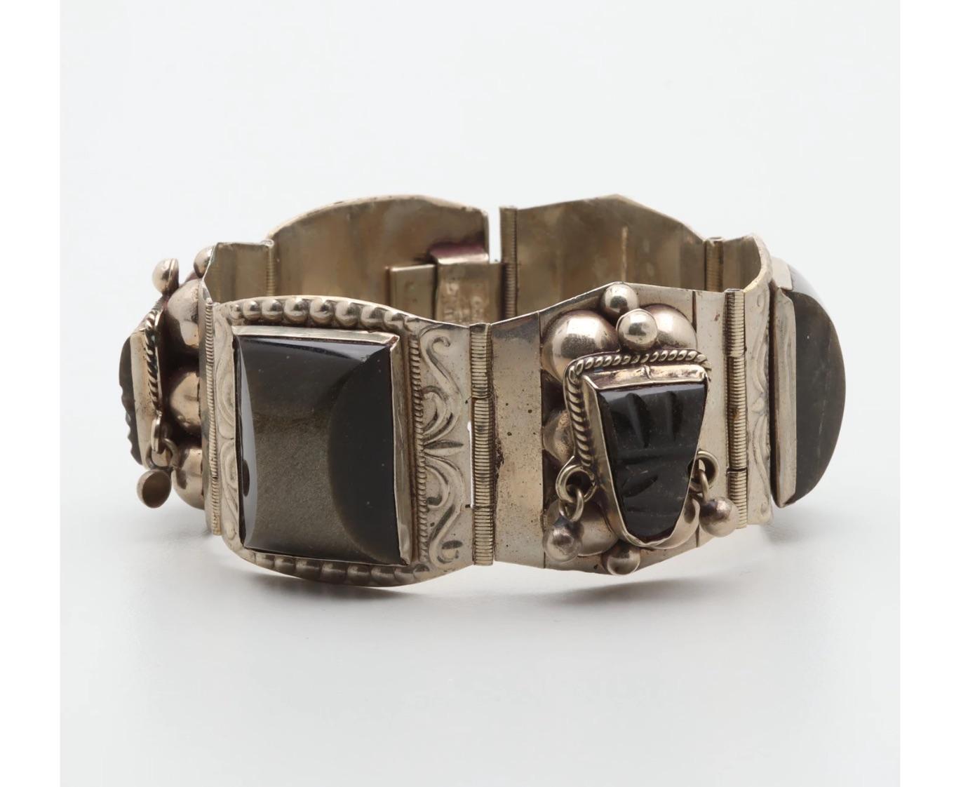 An attractive Sterling Silver Vintage 1950s Cuff Bracelet set with Carved and Rectangular Obsidian Cabochons alternating with Carved Obsidian Aztec Masks to embossed designs and round sterling silver beads and accented links.

Hallmarked-Sterling