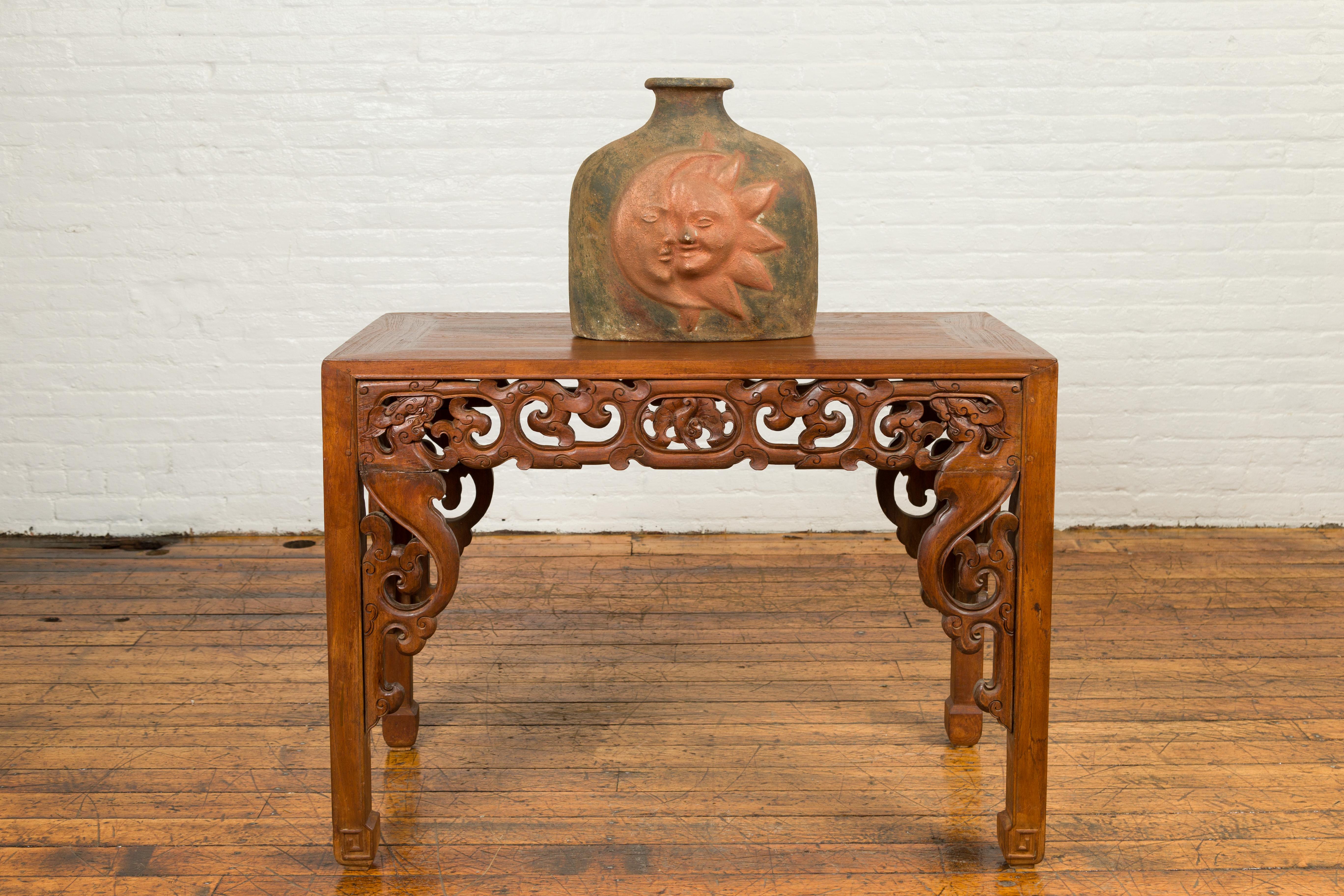 A Mexican sun and moon terracotta vase from the 20th century, with copper tones and thin lip. We are immediately drawn to the serene décor of this terracotta vase, showcasing an intertwining moon and sun highlighted with copper tones perfectly