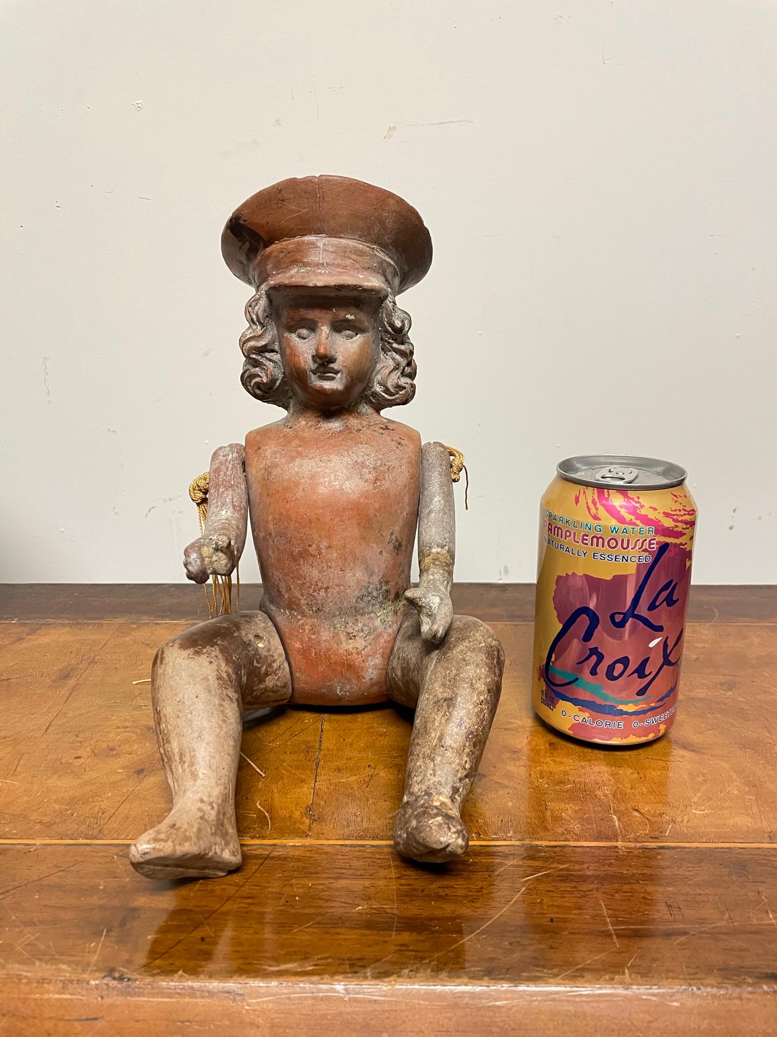Funky and very cool Mexican terracotta doll figure with articulated limbs. Since it is solid terracotta it is likely this is a mold from which other dolls were made. As a folk art sculpture it is absolutely charming. 
The military hat gives it a