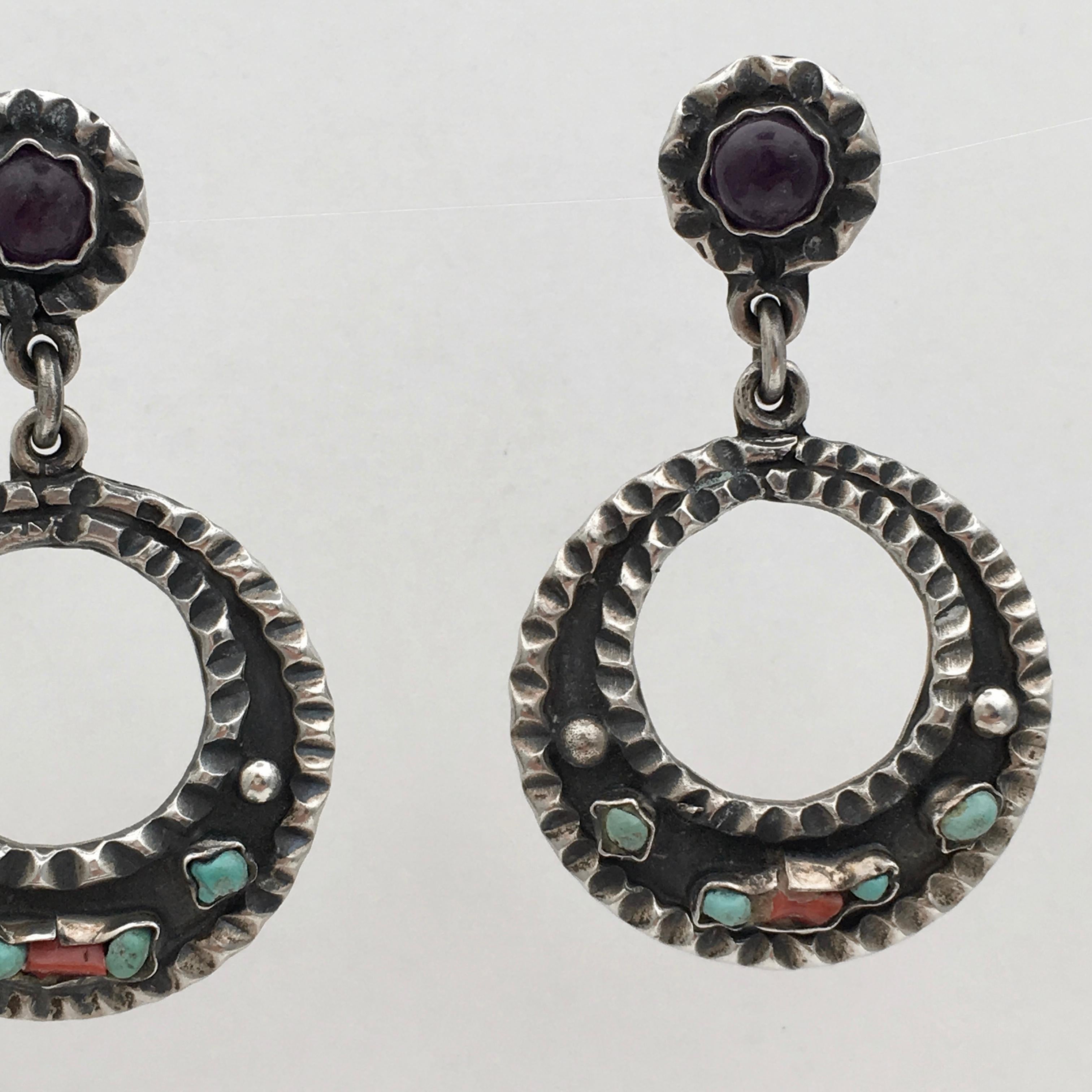 The bold design of this handcrafted pair of earrings embodies the essence of a trip to Mexico. Set with cabochon amethysts, turquoise and coral, they are colourful and eye-catching. The design is pleasingly articulated with a stylish bohemian edge
