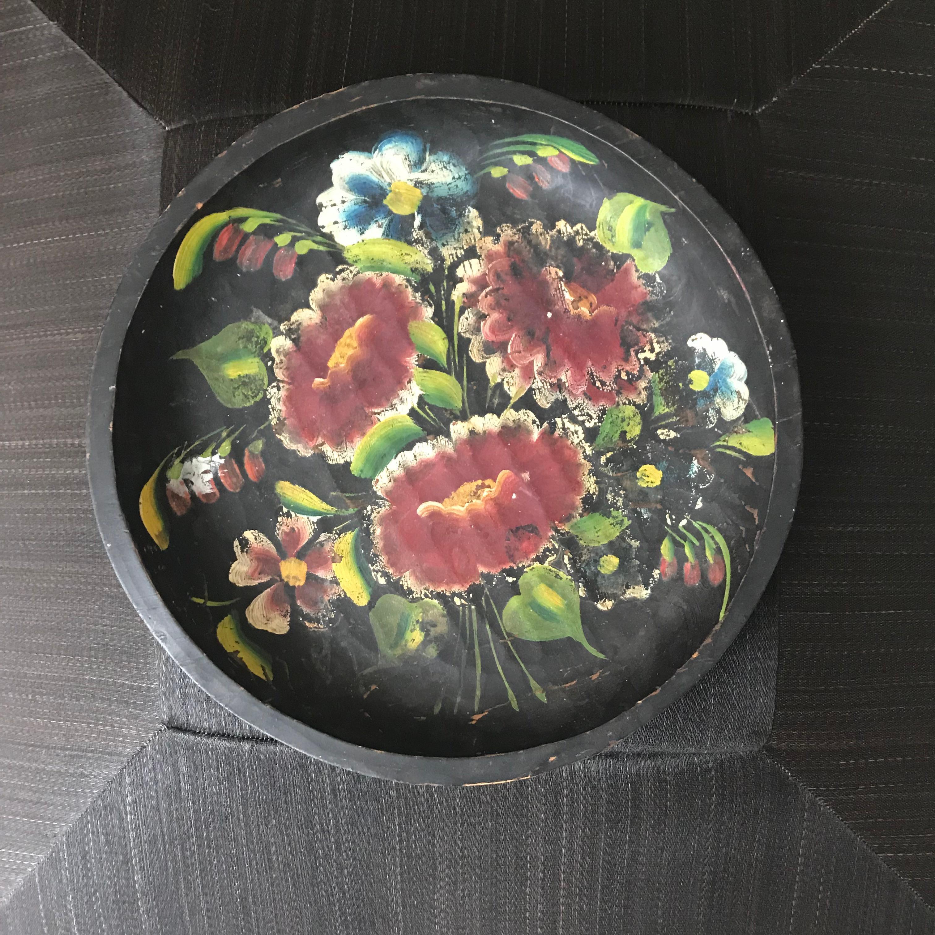 A beautifully crafted Mexican wooden plate featuring a black base and vibrant hand-painted flowers. This piece combines traditional craftsmanship with colorful artistry, perfect for adding a cultural touch to any space.