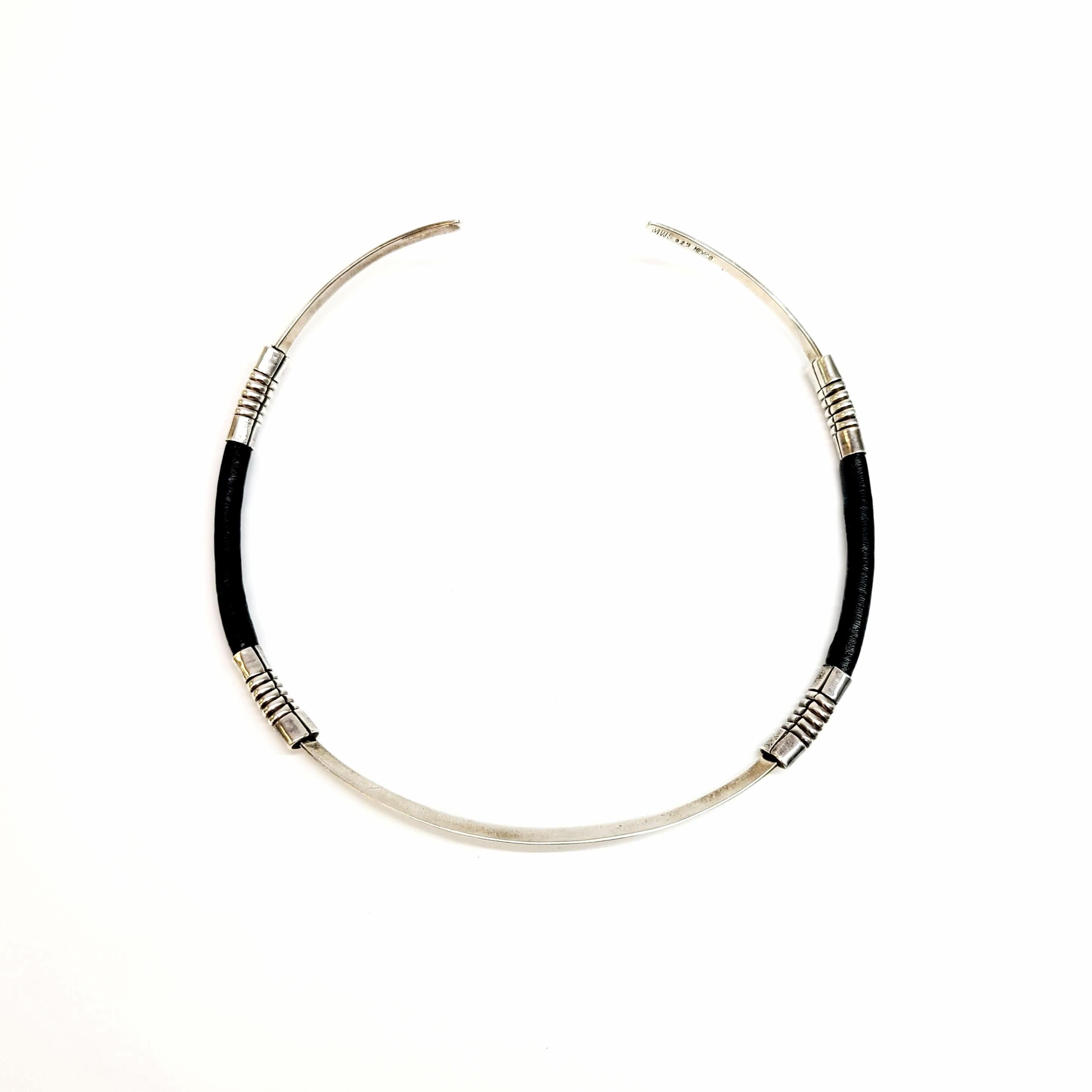 Signed MWS Mexico sterling silver and leather collar necklace.

Signed by Mexican artisan MWS, this piece features black leather wrapped around a thin sterling silver collar necklace with ribbed accents at each of of the leather sections.

Measures