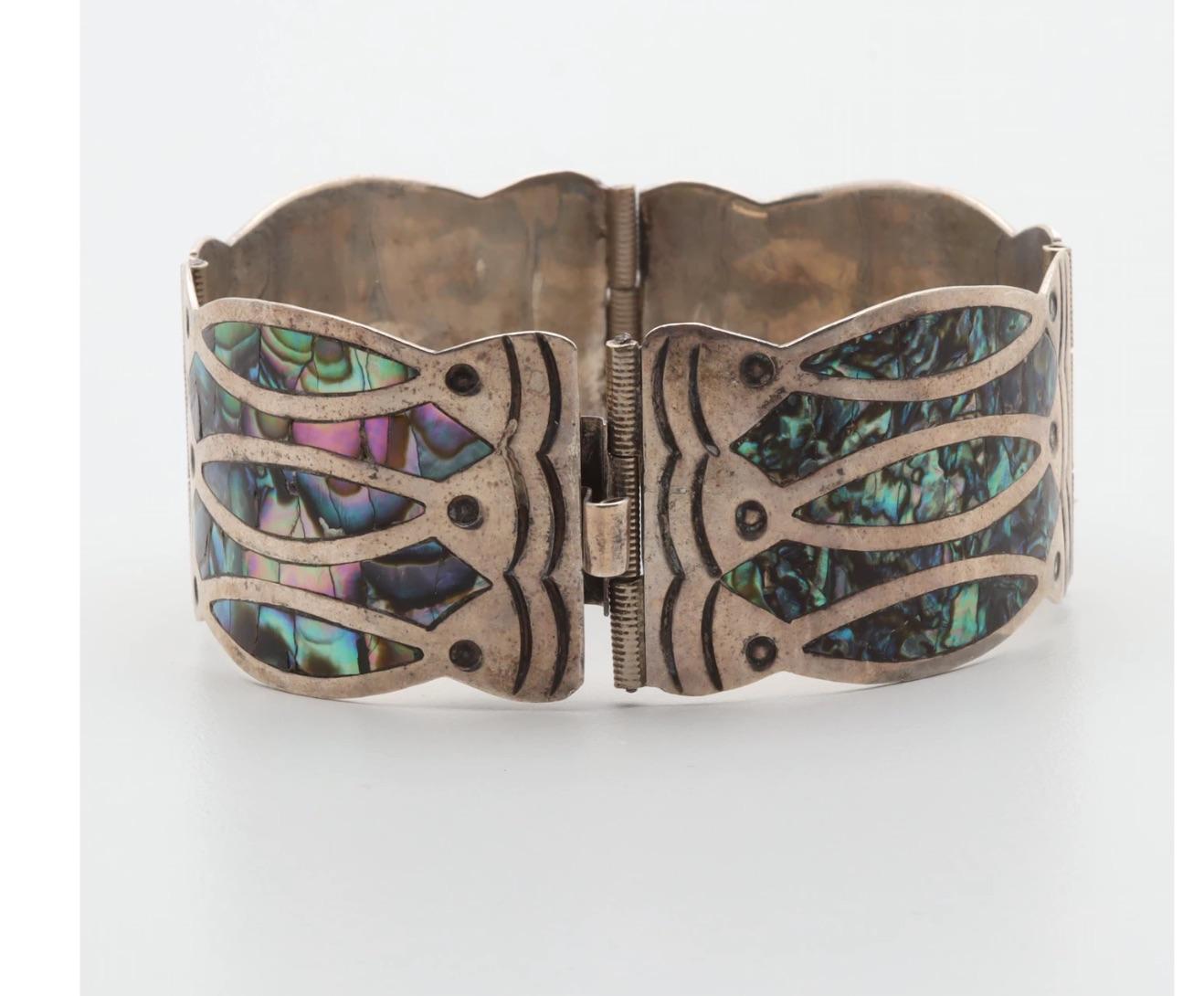 A beautiful unique circa 1940 Mexican Modernist Artisan Hand-Crafted branded sterling silver and abalone bracelet in a Fish Design.
Featured is a Diaz Santoyo bracelet inlaid and chased with a fish design of  abalone shell inlays to four contoured