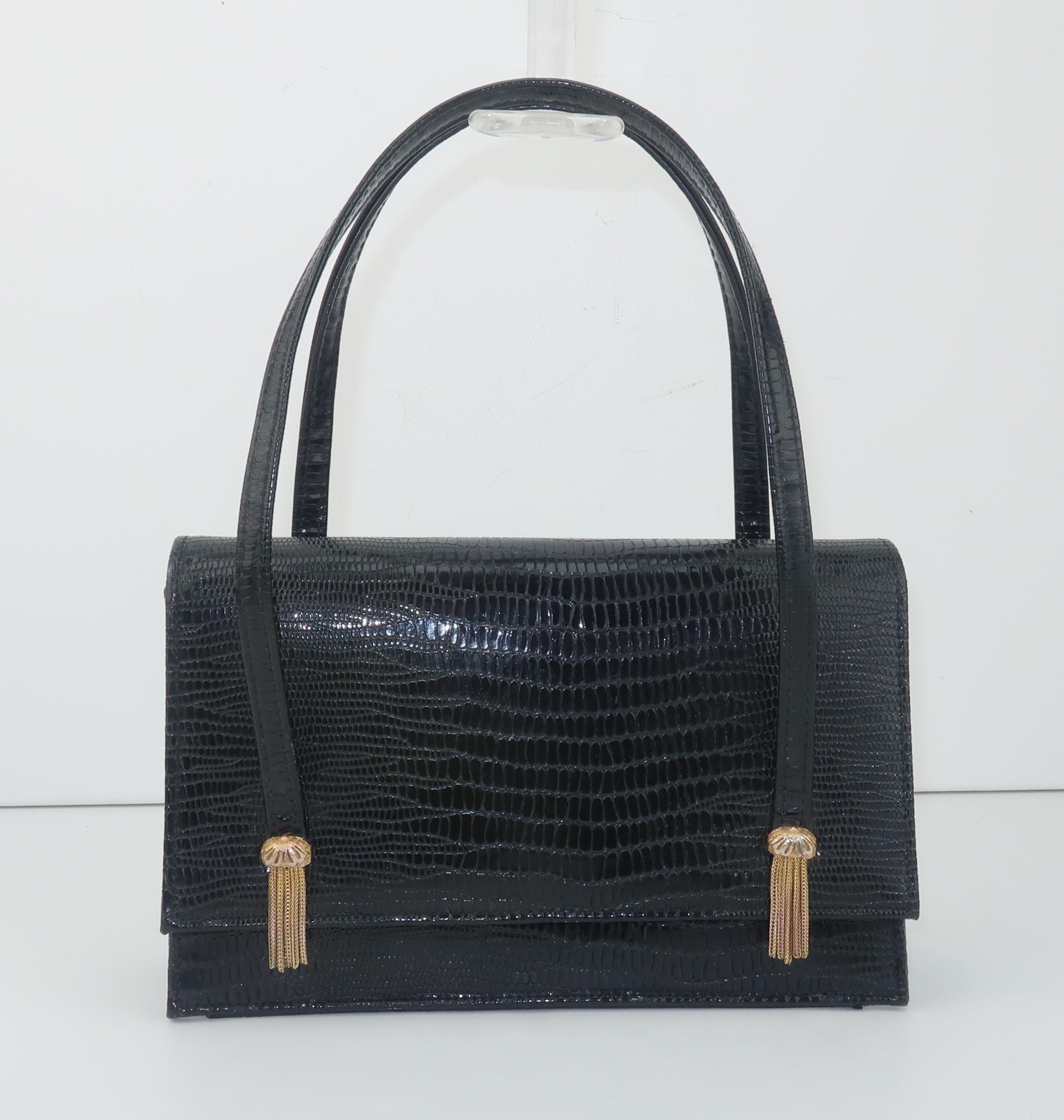 C.1960 Meyers black lizard embossed leather handbag with double handles and two decorative gold tone chain 'tassels'.  The bag snaps securely at the front and opens to a vinyl lined interior with open side pockets trimmed in gold.  Originally