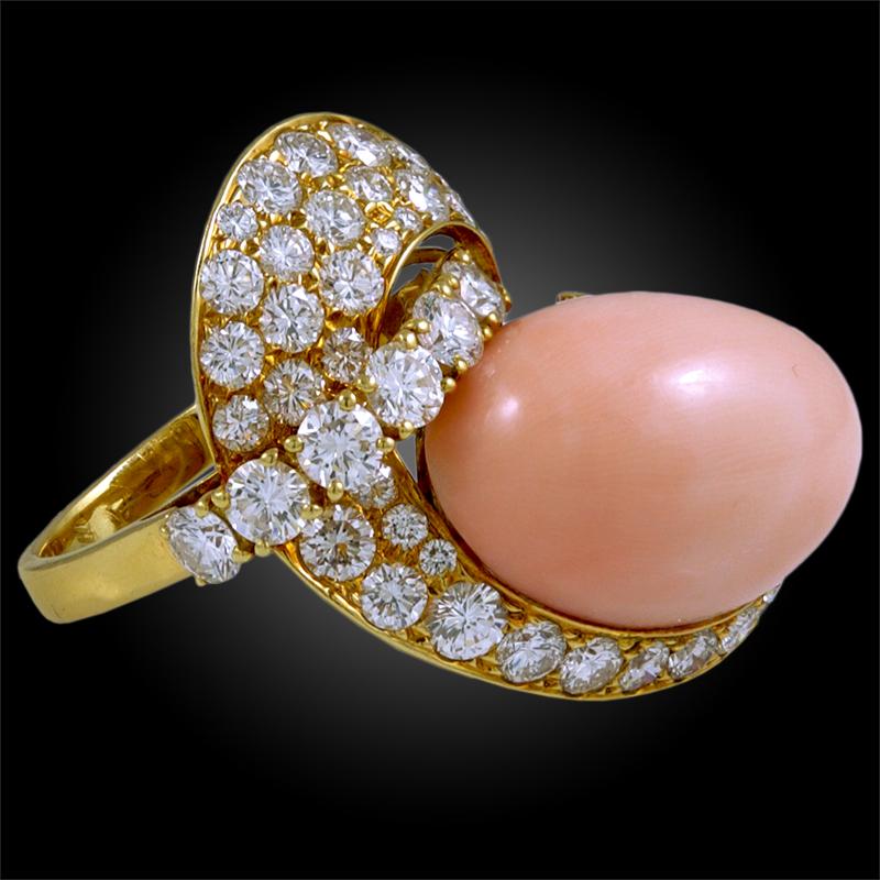 An exceptional ring with a unique design crafted by M. Gerard, dating back to the 1970s, comprising a large oval shaped angel skin coral surrounded by brilliant round cut diamonds mounted in an 18k yellow gold twist design.