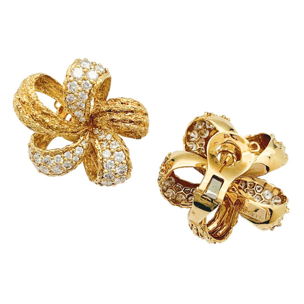 A 18K yellow gold pair of M.Gérard earrings, drawing ribbon flowers, partially enhanced with brilliant cut diamonds. The earrings have a clip mechanism. Each earring holds 36 brilliant-cut diamonds in a bead setting. The diamonds range from F to G