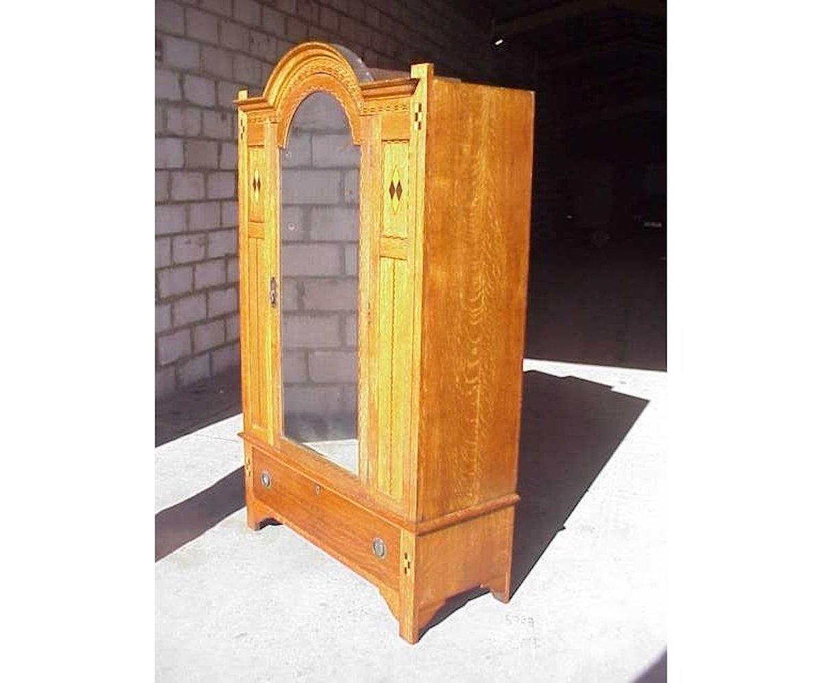 M H Ballie Scott style, Shapland & Petter.
An Arts & Crafts oak wardrobe with domed top and conforming dome top door with full length bevelled mirror and lower full length drawer, the whole inlaid with a variety of diamond and chequer inlay with