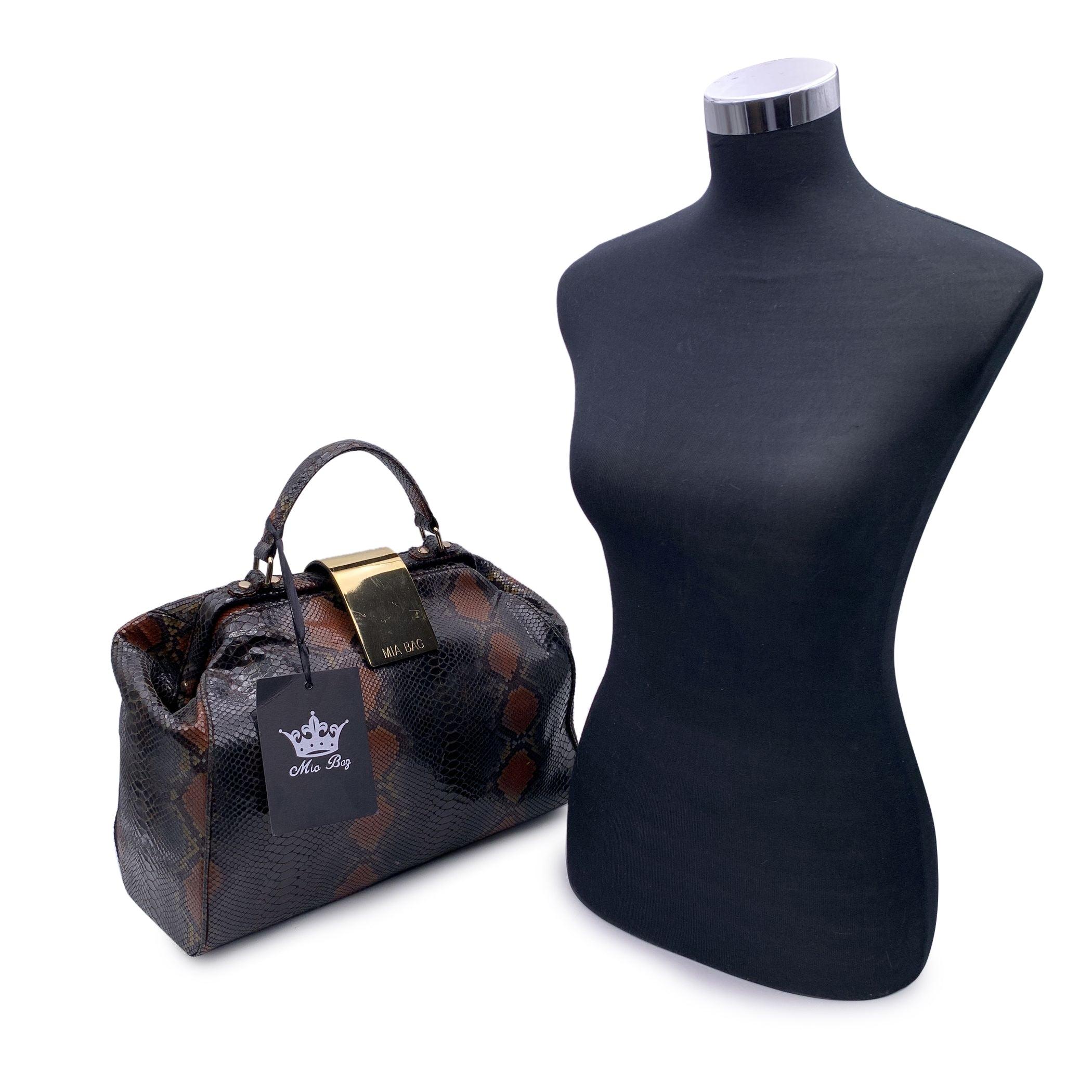 Beautiful doctor bag signed Mia Bag. Snake printed canvas. Framed top with top carry handle and removable shoulder strap. Fold over gold metal plaque with magnetic button closure. Signature lining. 1 side zip pocket inside. Condition A - EXCELLENT