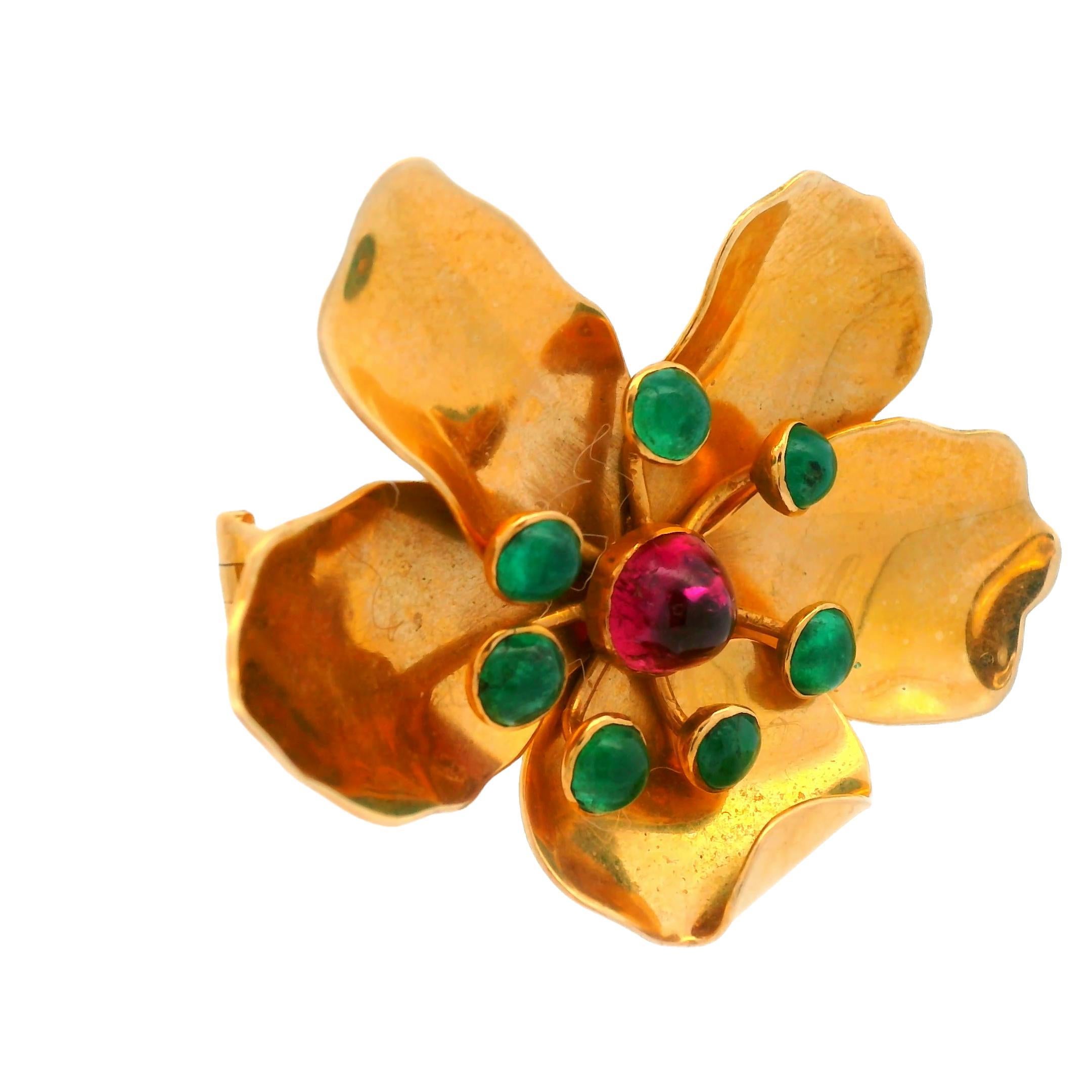 This is a rare mid-century modern tourmaline and enamel flower brooch made by Mic Neugel. The 18k yellow gold flower is detailed to appear life-like and looks especially beautiful under sunlight. The beautiful green emerald and pinkish-purple