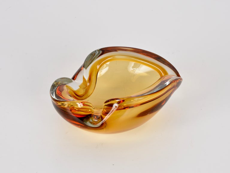 Magnificent midcentury Murano Art Glass with astonishing colour shades going from dark red to amber, via light orange and crystal. This piece was produced in Italy during the 1960s.

This wonderful piece is the perfect mix of sinuous lines and