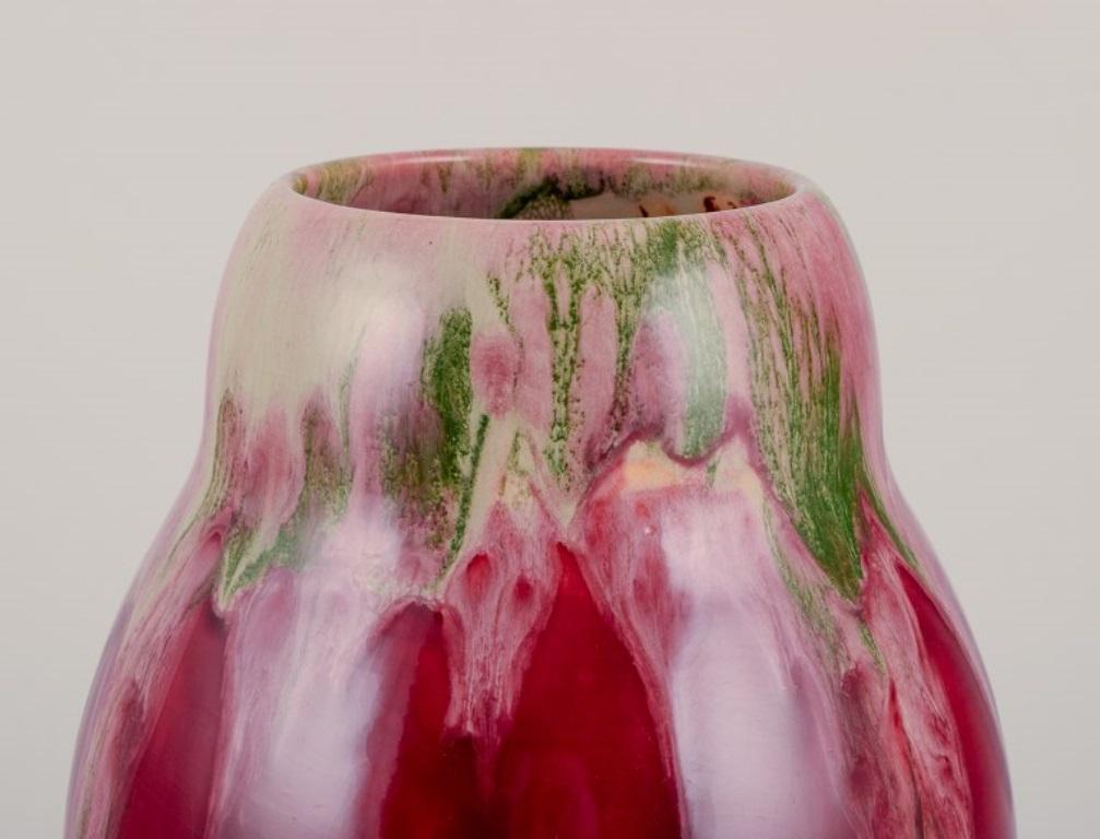 Michael Andersen, Bornholm. 
Large vase in ceramic. 
Floating glaze in violet and green shades.
Model 1409.
Mid-20th century.
Marked.
Perfect condition.
Dimensions: Height 26.0 cm. x Diameter 15.0 cm.