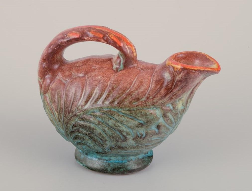 Michael Andersen (1859-1931), Bornholm. 
Petite cruche en céramique. 
Glaçage dans les tons de brun, de bleu et de vert.
Modèle 5147.
A.I.C., milieu du XXe siècle.
Marqué.
Parfait état.
Dimensions : L 13,0 cm. x H 10,0 cm : L 13.0 cm. x Hauteur 10.0