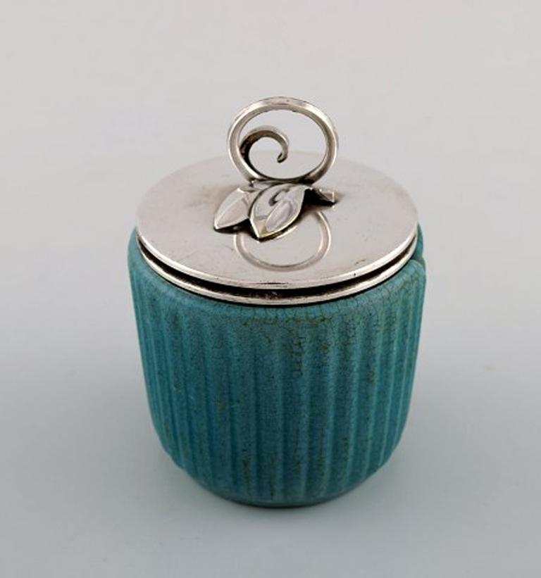 Michael Andersen, Denmark marmalade jar in ceramics, fluted style with plated silver lid and silver spoon by Hans Hansen.
Green/blue glaze. Hugo Grün silver lid (plated). Hans Hansen, Denmark silver spoon.
Measures 10 cm x 7.5 cm. (incl. lid)
In