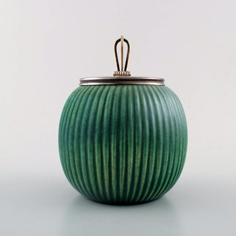 Michael Andersen, Denmark marmalade jar in ceramics, fluted style with plated silver lid and silver spoon by Georg Jensen (Pyramid).
Green glaze.
Measures: 13.5 cm x 10 cm. (incl. lid)
In very good condition.