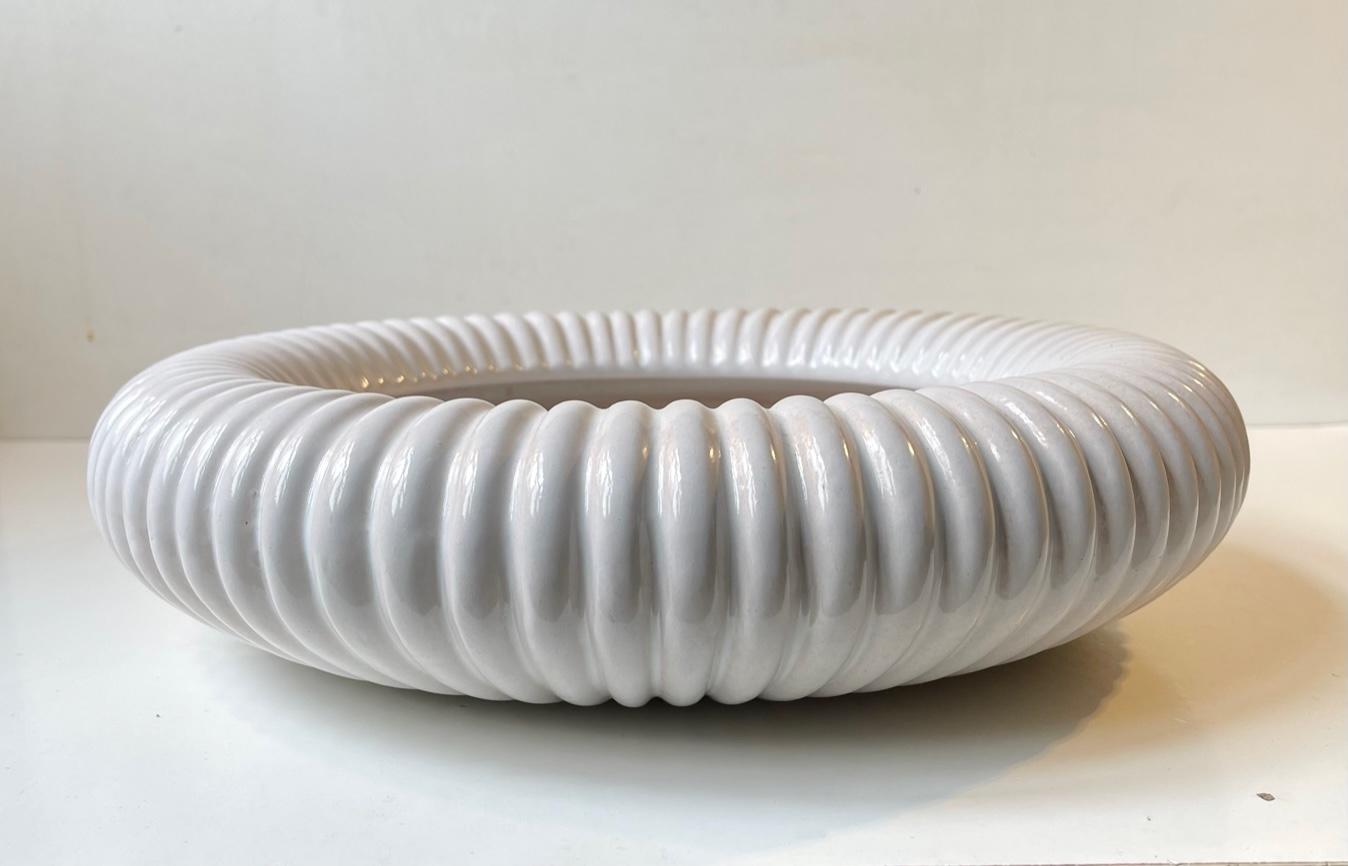 Very rare large fluted centerpiece Bowl from Michael Andersen & Son. Executed in white glazed pottery richly decorated with vertical ribbing. The style is reminiscent to Arne Bang, Just Andersen and Eslau. Its signed by the maker to the base.