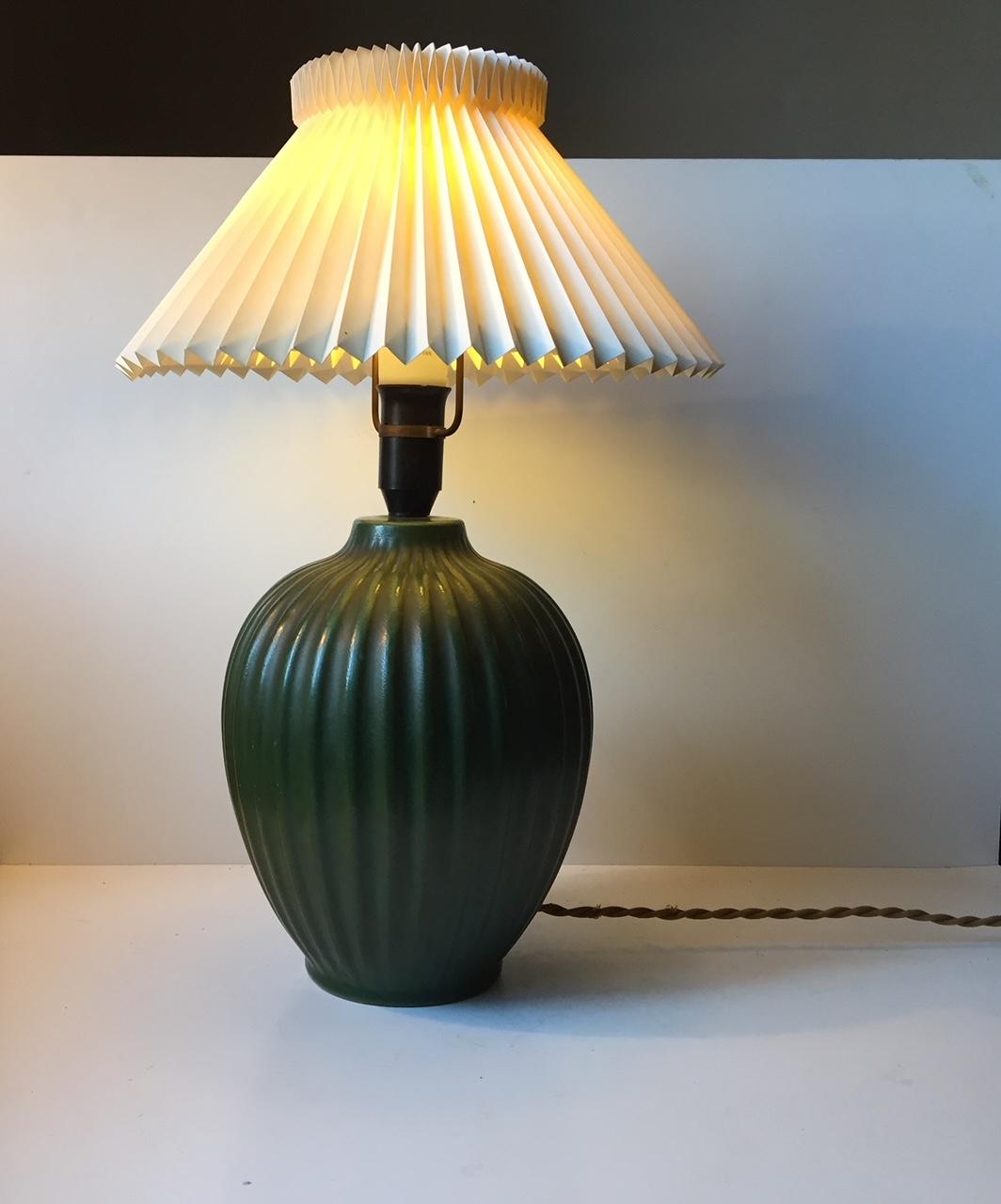From a distance this lamp looks like its made of bronze. However its all ceramic that has been applied with a verdigris green glaze to its vertically fluted body. This rare table lamp base was made by Michael Andersen in Denmark during the late