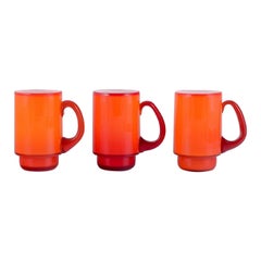 Michael Bang für Holmegaard. Drei Tassen aus orangefarbenem und weißem Kunstglas. 1960er Jahre