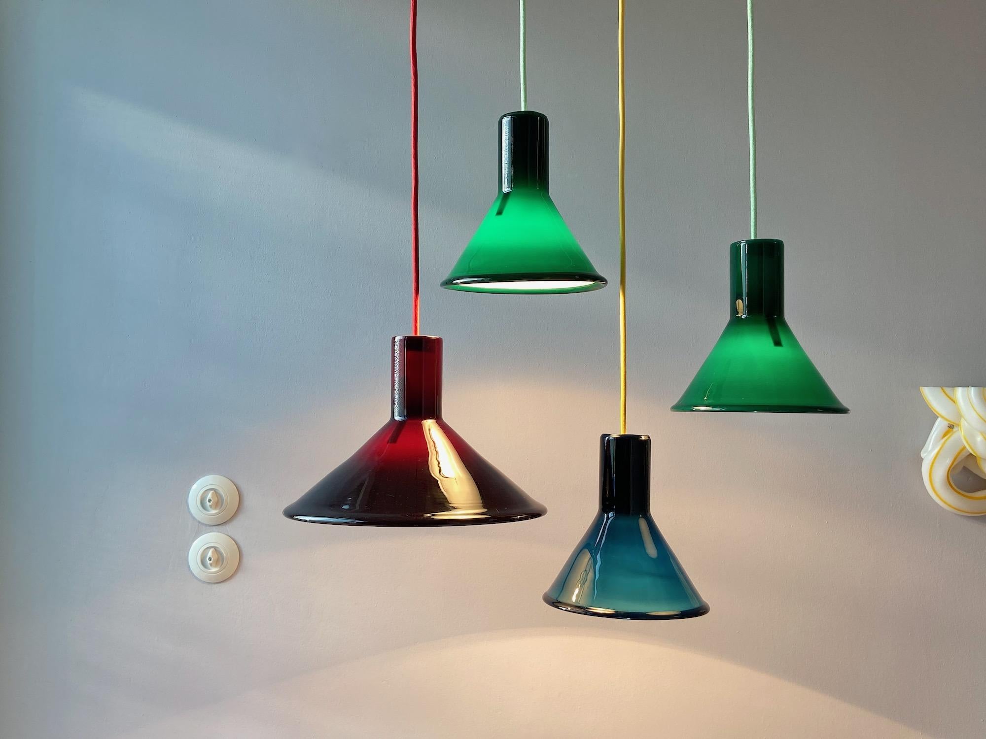 P&T pendant lamp designed by Michael Bang for Holmegaard in the 1970s. This Danish lamp is made of opaline glass and is black/aubergine on the outside and white on the inside. The lamp is in very good condition, no damages and comes with red fabric