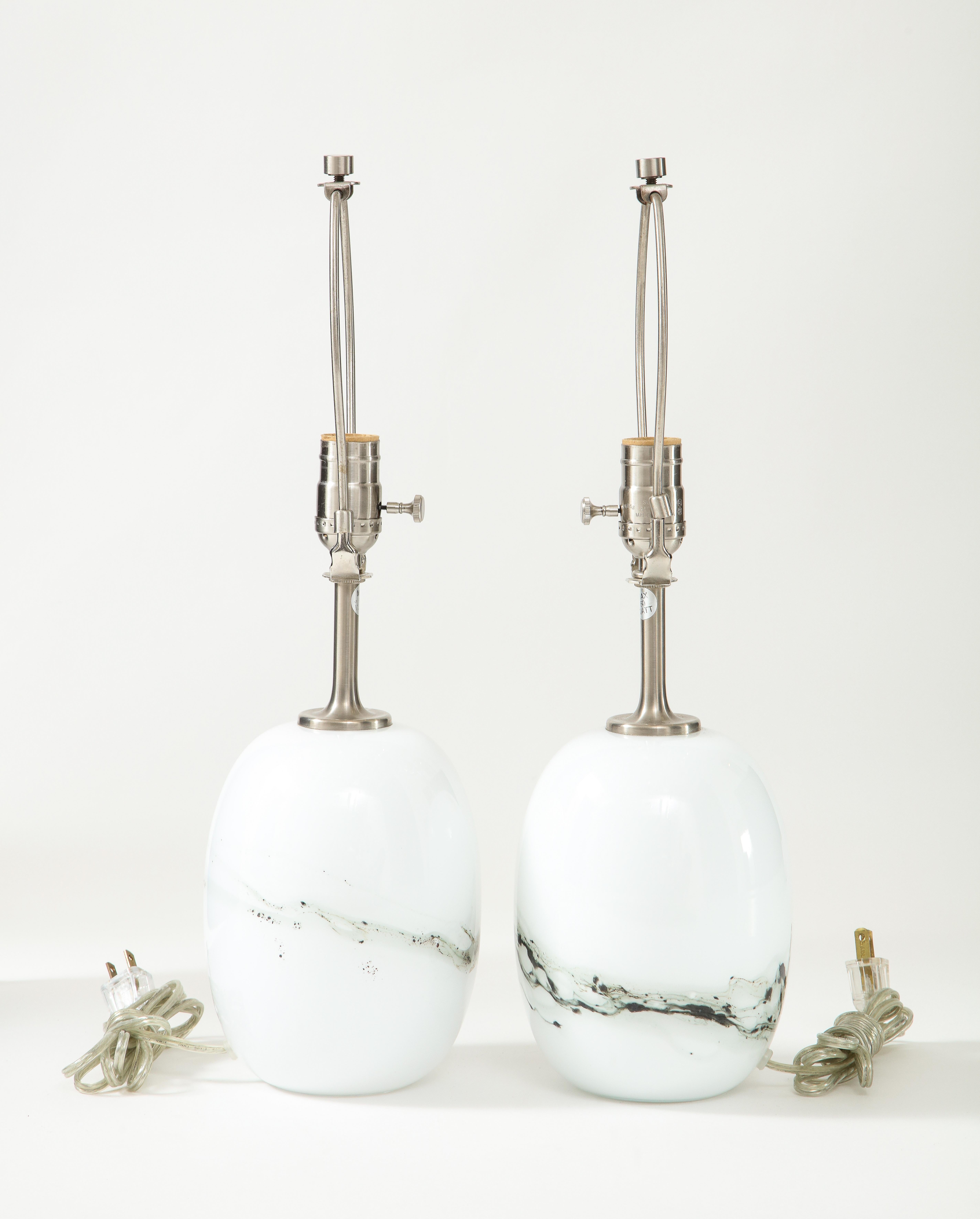 Pair of Scandinavian Modern oblong orb shaped white glass lamps with grey glass threads circling the center. Lamps have satin finished necks and have been rewired for use in the USA. Michael Bang for Holmegaard.