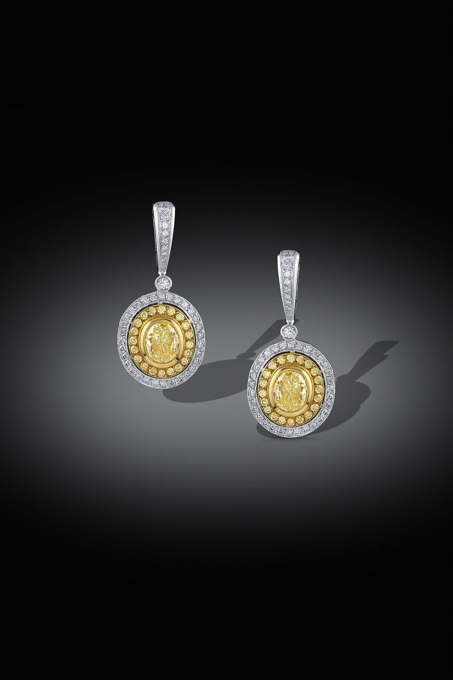 Earrings with perfectly matched 1.07ct and 1.06ct GIA certified fancy yellow oval cut diamonds. There are additional yellow and white diamonds in the 18k yellow and white gold settings. The total diamond weight is 3.05cttw.