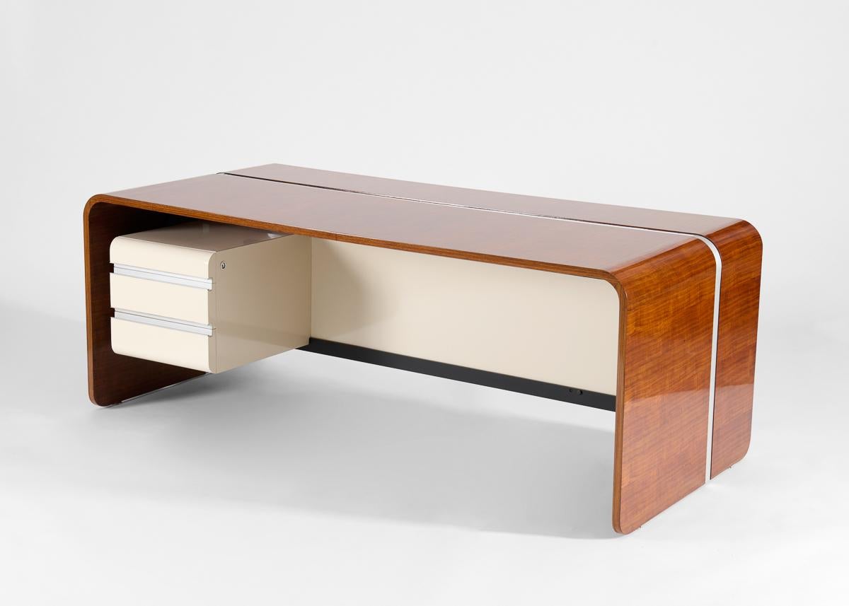 Una cucitura di alluminio attraversa la superficie continua di ricco mogano che contrasta con il laminato bianco sottostante. Con l'etichetta del produttore DESSIN Michel BOYER mobilier national EDITEUR T.F.M.