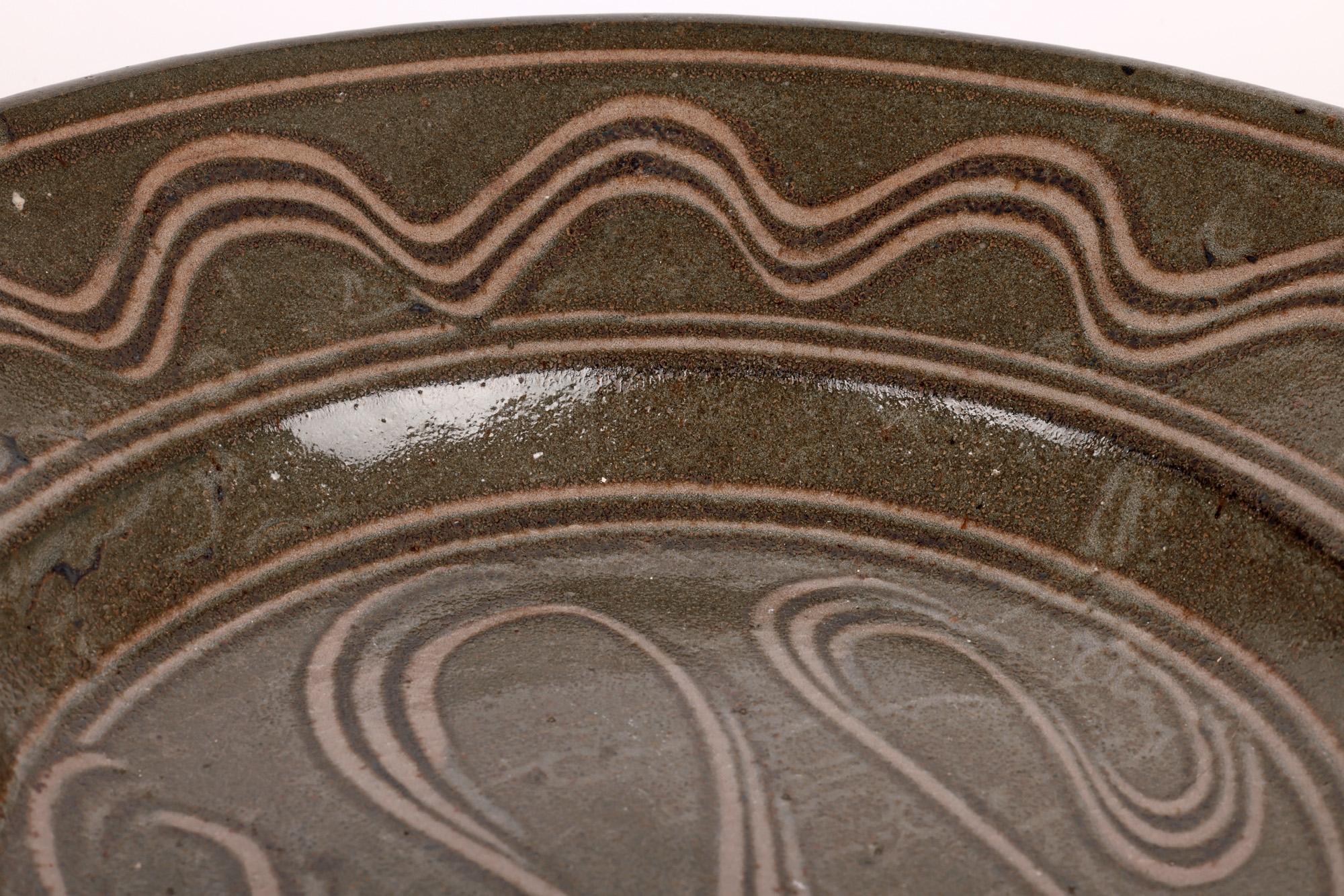 A large and impressive studio pottery stoneware dish decorated with a combed design by Michael Cardew (British, 1901-1983) and made at Wenford Bridge around 1975. The dish is quite lightly potted and is of wide round shape with a recessed central