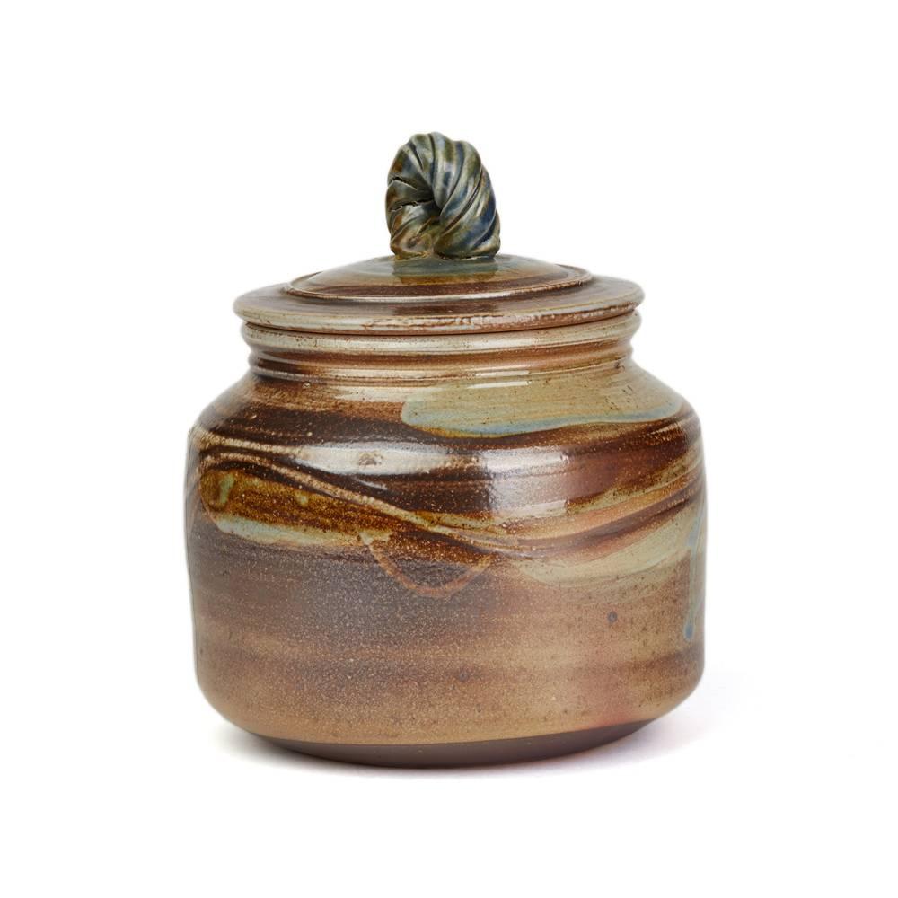 A stunning vintage British studio pottery jar and cover by renowned potter Michael Casson (1925-2003). The stoneware jar is of rounded shape with a slightly domed cover with a twist handle decorated in brushed brown colors on a stone ground with a