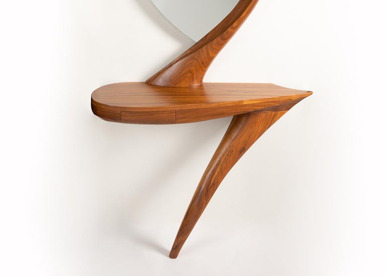 This remarkable wall-mounted console is hand carved from black walnut and features almond shaped, inset mirror. Coffey, a master craftsman based in western Massachusetts, took his inspiration from the Heron, endowing his work with the creature's