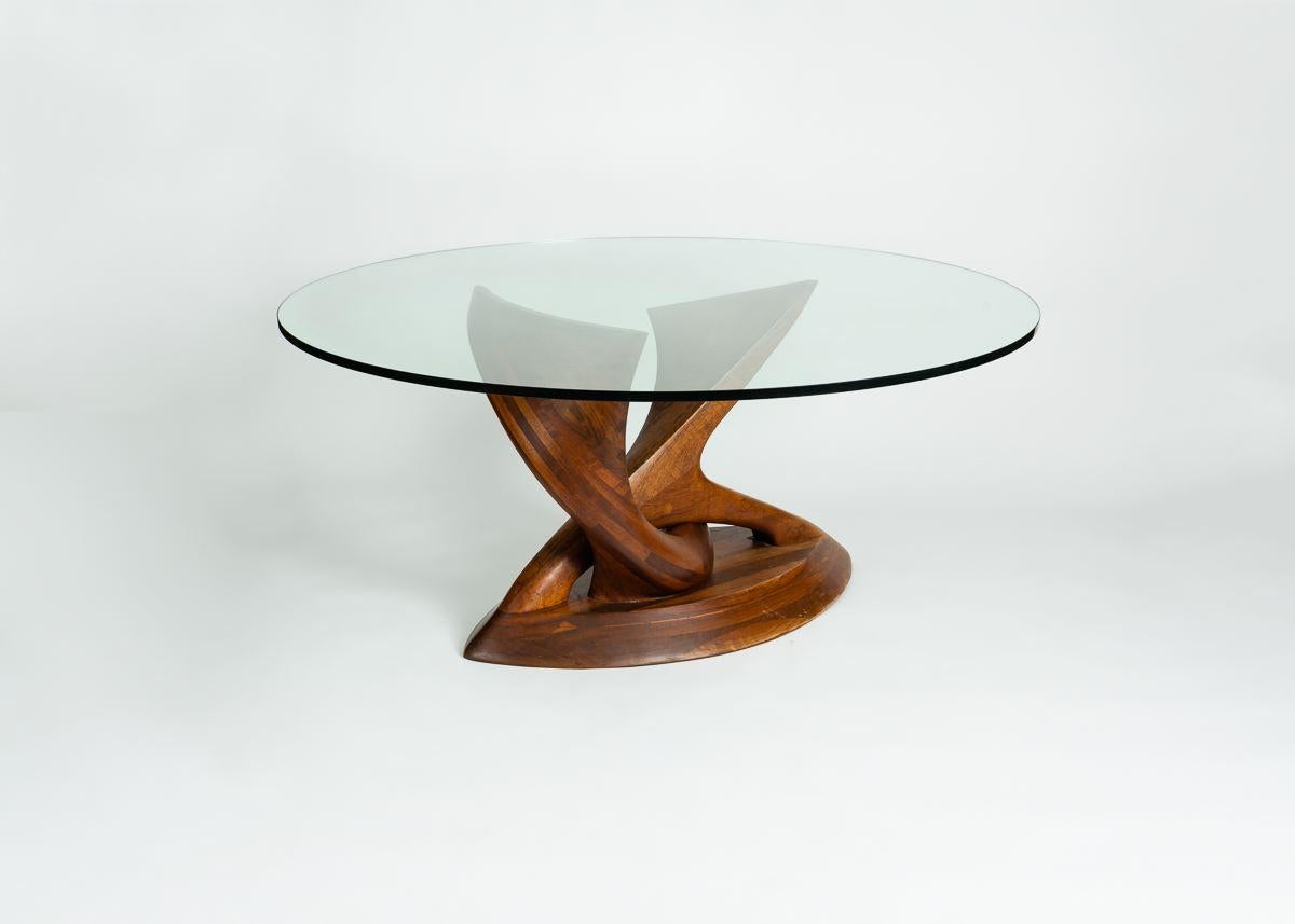 Sculpted in the early 1970s from a rare Mozambique wood, this is one of the very first of Michael Coffey's twisting dining tables. The two supports of this exceptional table rise from its almond shaped base, intertwined in a kind of dance, and endow