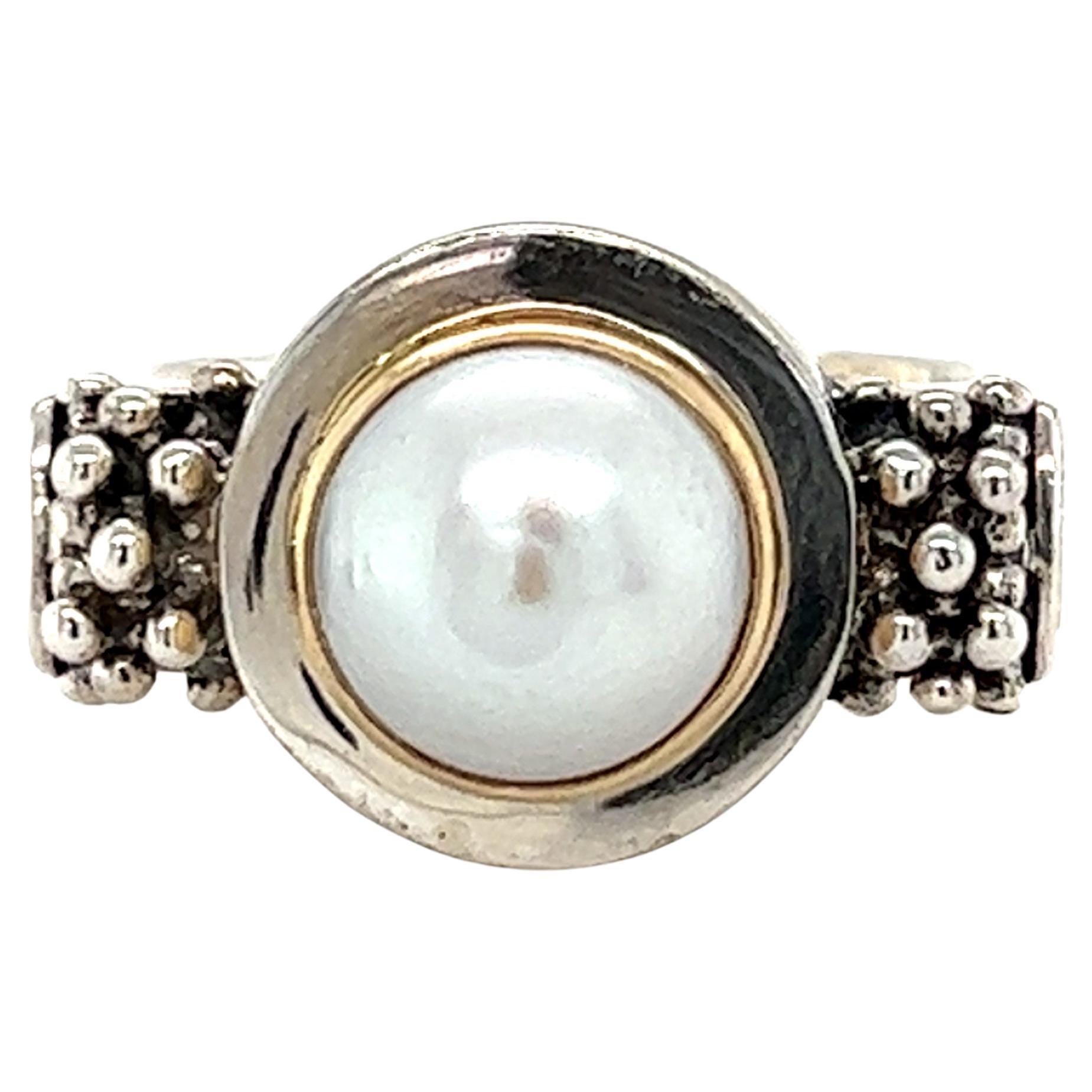 One sterling silver and 14 karat yellow gold (stamped 925 14KT Michael Dawkins) Michael Dawkins ring, set with one 8.8mm bezel set freshwater button pearl.  The ring measures 14.13mm at the top of the ring and tapers to 5.79mm at the base.  The ring