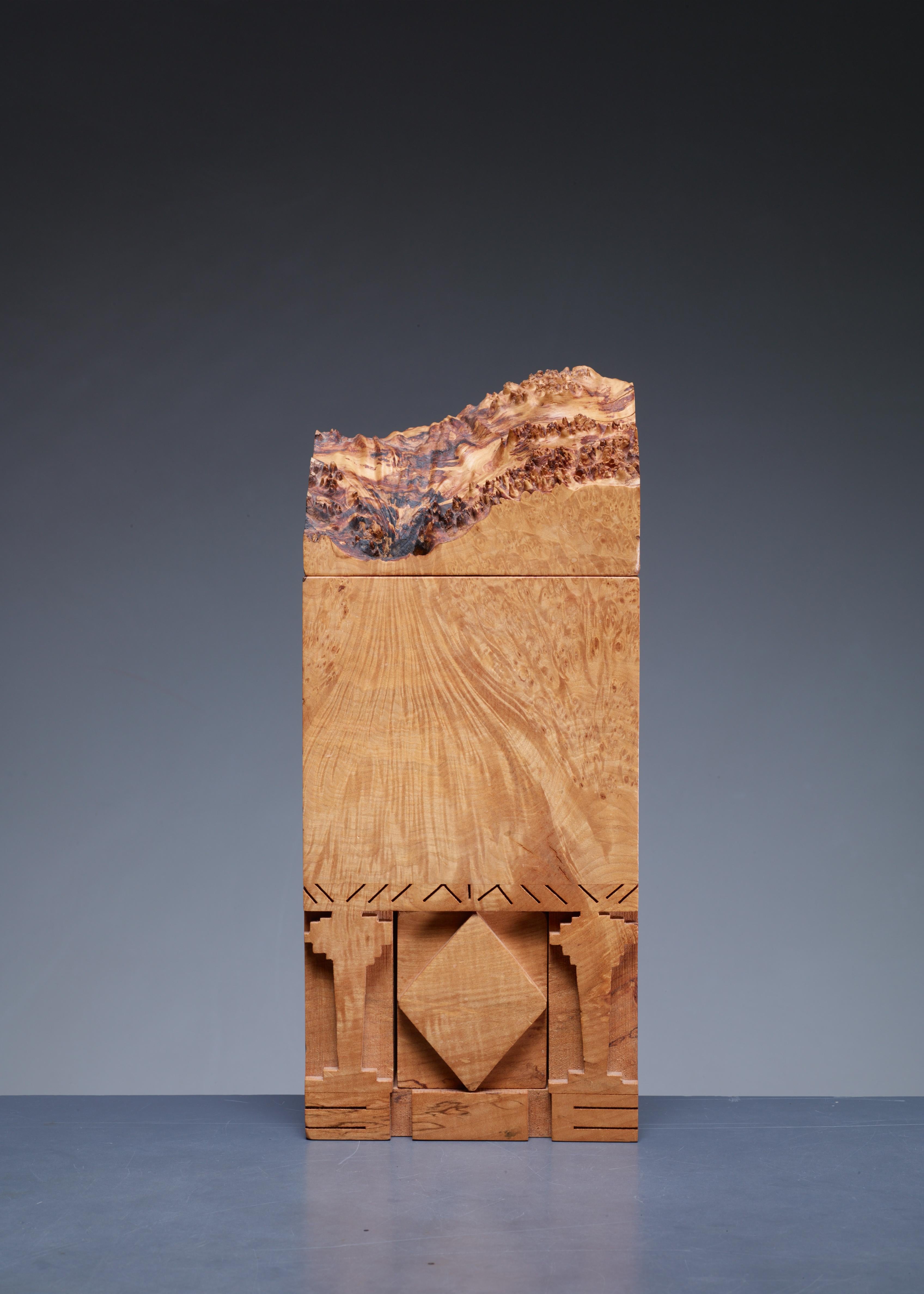 A small, sculptural box of maple burl with two lids, by American craftsman Michael Elkan. Marked by Elkan underneath.
In the words of Elkan, his boxes are “[…] inspired by caverns, bridges, masks & trees [...] Led by the wood in an exploration of