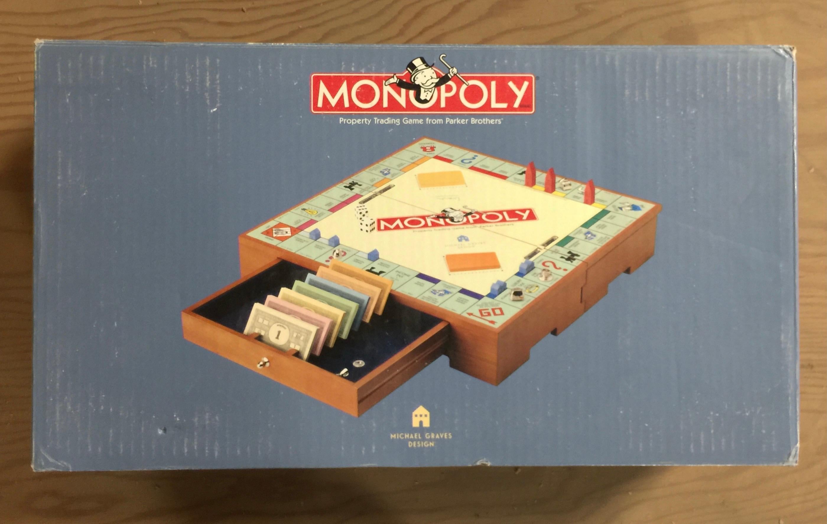 The Monopoly game set designed by Michael Graves (b. 1934 Indianapolis, IN - 2015 Princeton, NJ) for Parker Brothers. Circa 2002. 

Signed with Graves' signature incised in small metal disk on underside.

Features a cherry-finished wood box that