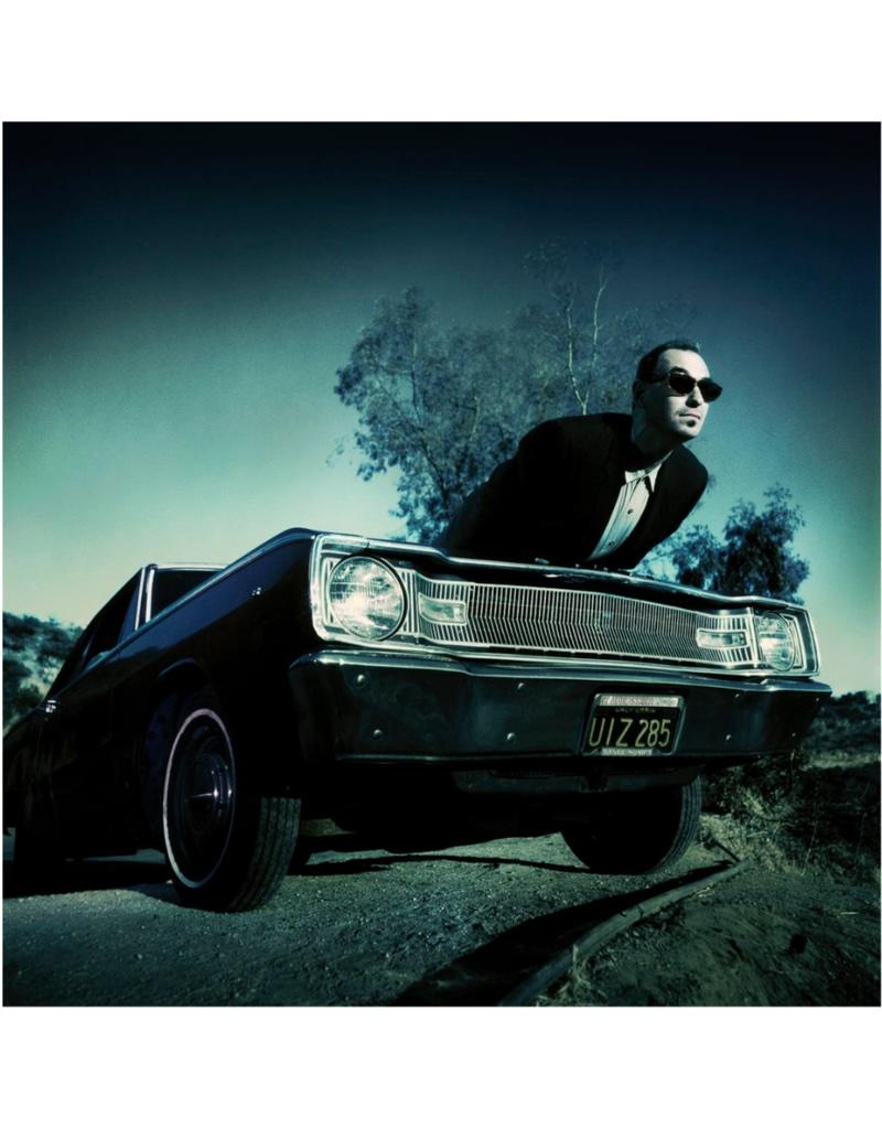 Portrait Photograph de Michael Grecco - Barry Yourgrau - Posa para un retrato encima del capó de un coche, 1991